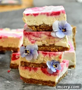 Two halves of a No-Bake Lemon Raspberry Bar, showing the creamy texture and the swirl, on a small white plate with a fork.