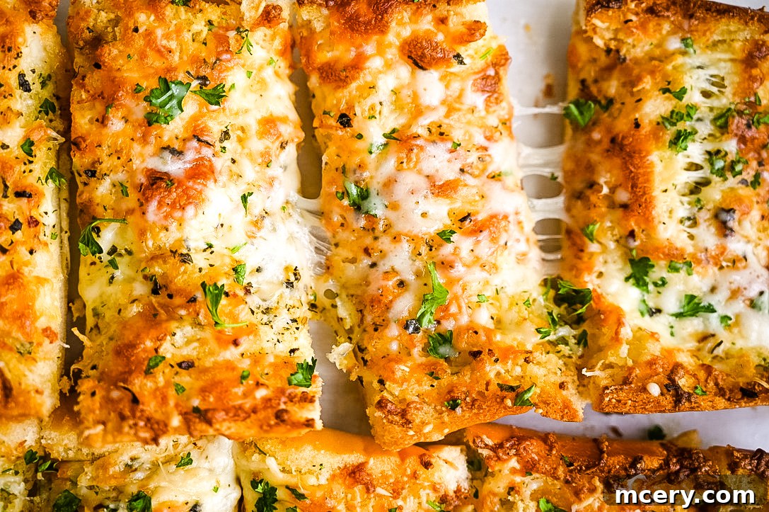 Freshly baked cheesy garlic bread, cut into thick slices and stacked on a white plate. The bread is golden-brown with melted, bubbly cheese and sprinkled with green parsley. A few individual slices are arranged artfully, inviting immediate enjoyment.