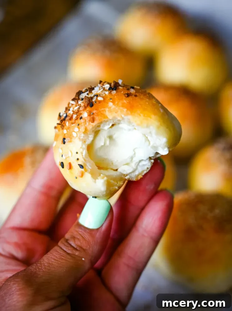 Bagel Bombs 14 A hand holding a freshly baked stuffed bagel bite, with a soft, warm interior visible.