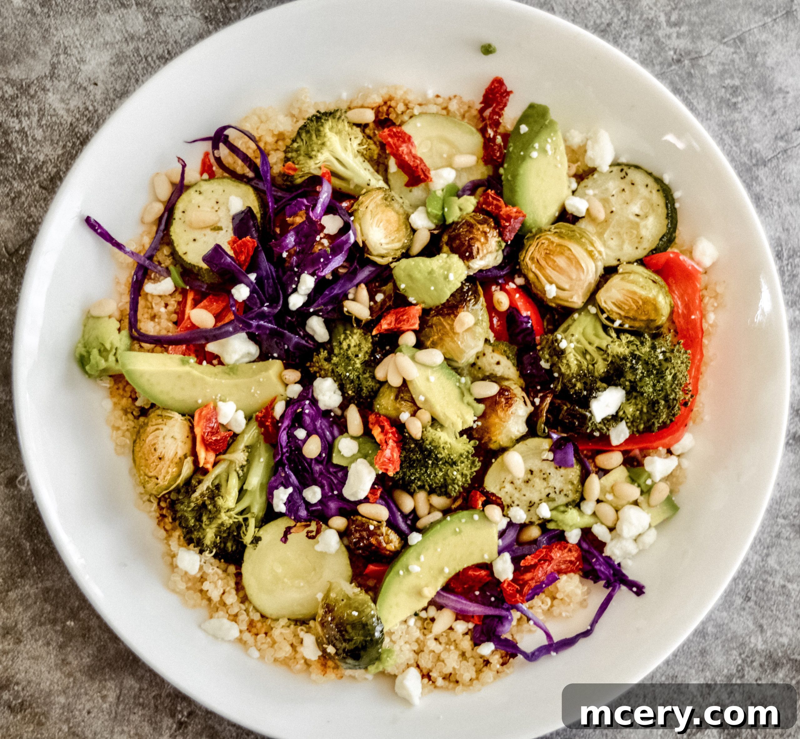 Wholesome Roasted Vegetable Quinoa Bowls 4 A visually appealing selection of fresh vegetables—including sliced zucchini, bell peppers, purple cabbage, and Brussels sprouts—arranged artistically on a light surface, highlighting the fresh ingredients before roasting.