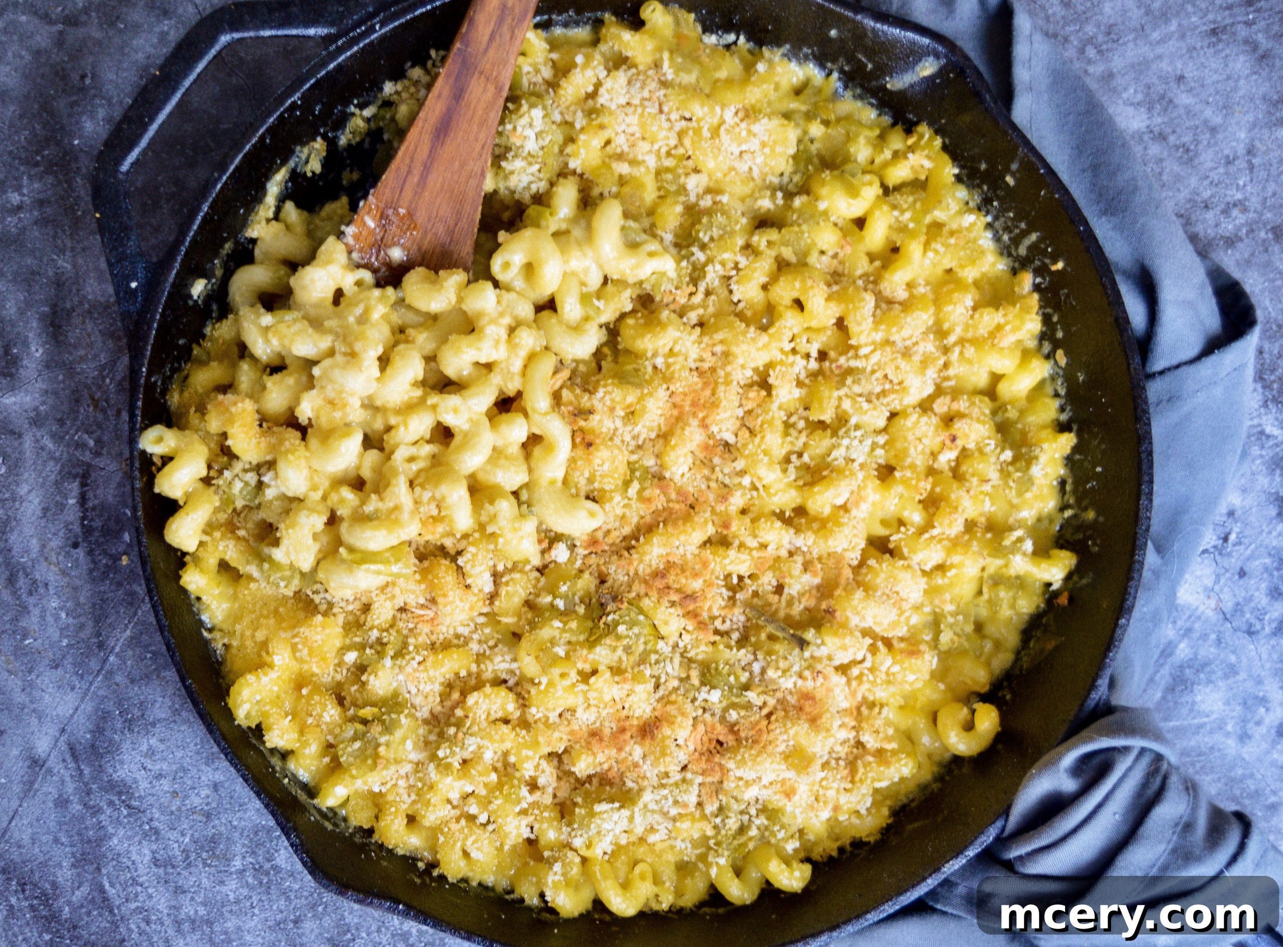 Close-up of a bubbling skillet of Hatch Green Chile Macaroni and Cheese, garnished with fresh cilantro.