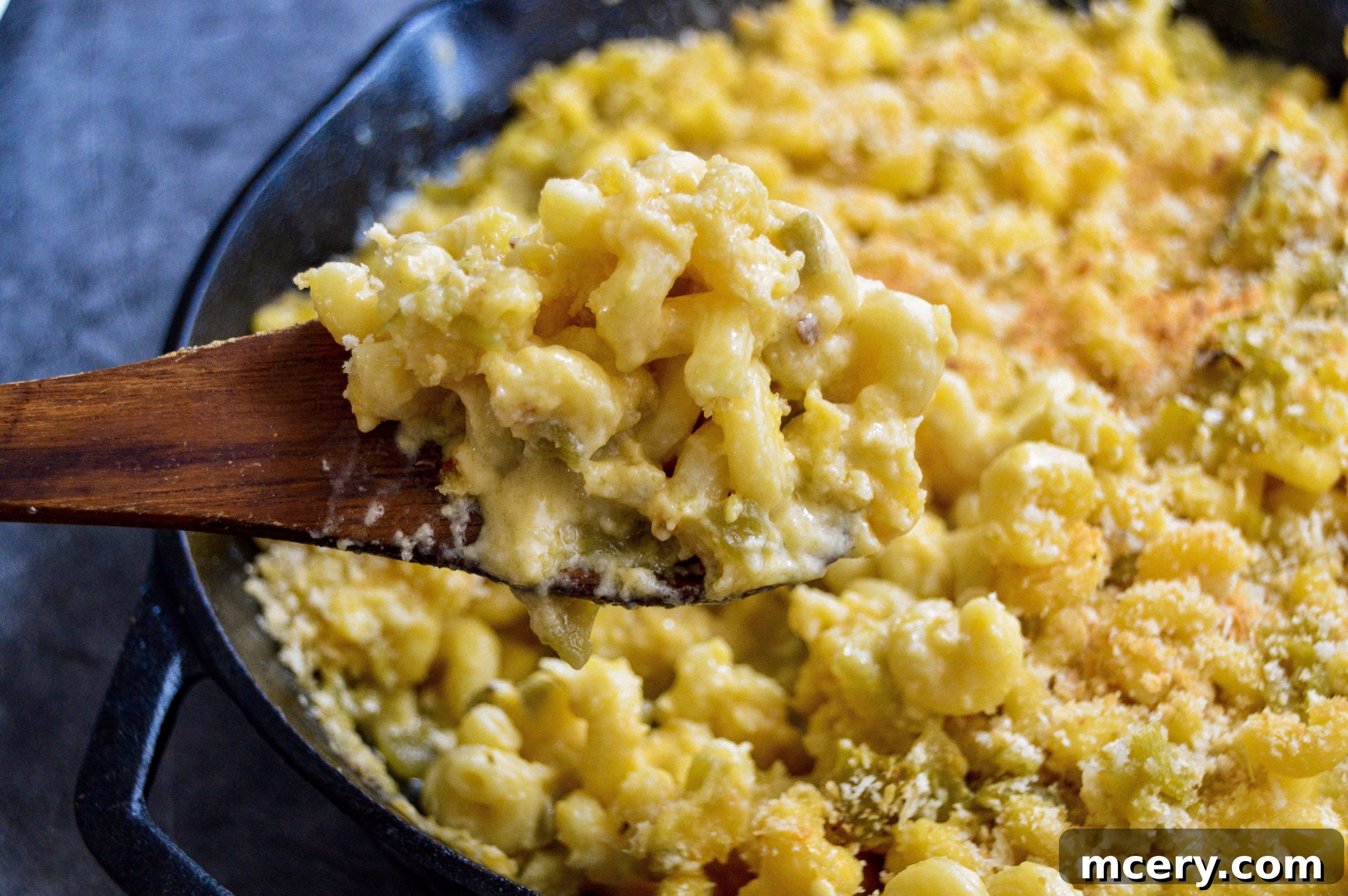 A generous serving of Hatch Green Chile Macaroni and Cheese scooped into a bowl, showcasing the rich cheese sauce and green chile pieces.