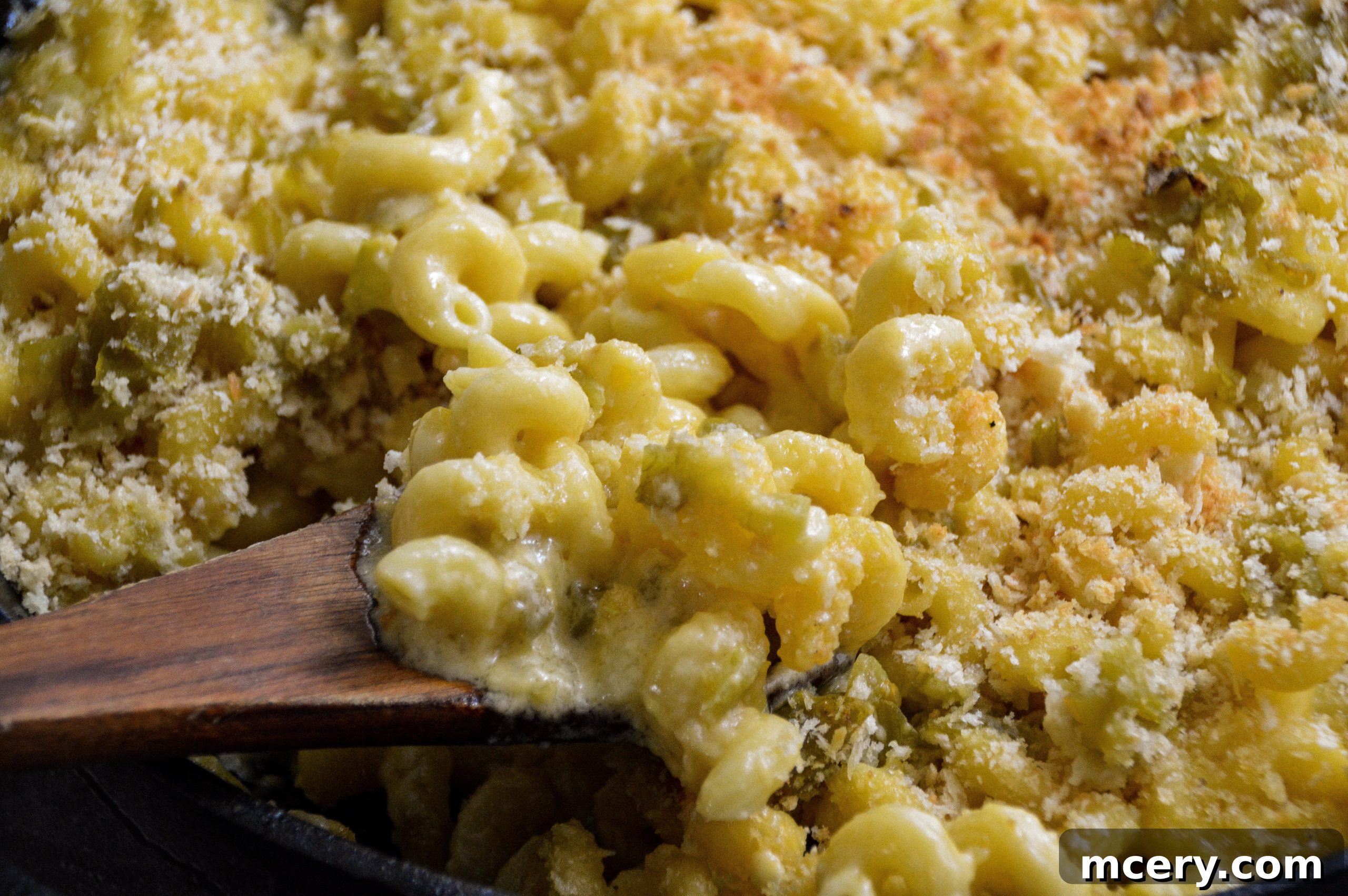 A fork taking a bite of creamy Hatch Green Chile Macaroni and Cheese, showing the pasta and melted cheese.