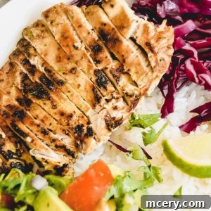 Citrus Pollo Asado Bowl with Avocado Salad, steamed white rice with lime wedges, red cabbage, and a side of avocado and tomato salad garnished with cilantro. The meal is arranged on a white plate on a stone surface.