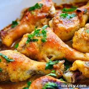 Sticky Honey Mustard Glazed Chicken Drumsticks 12 Close-up of cooked Honey Mustard Baked Chicken Drumsticks garnished with fresh parsley in a rich, golden-brown sauce. The chicken is seasoned and has a crispy, golden skin, surrounded by a flavorful broth.