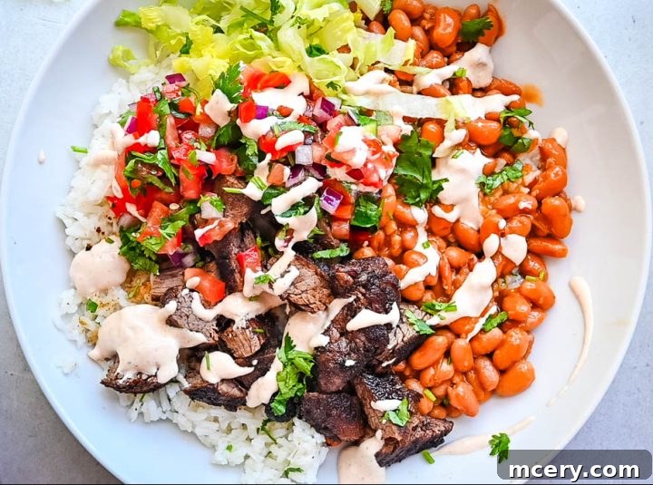 Smoky Chipotle Steak Bowls 2 A vibrant steak burrito bowl featuring tender steak, fresh greens, corn salsa, and creamy sauce over a bed of cilantro lime rice.