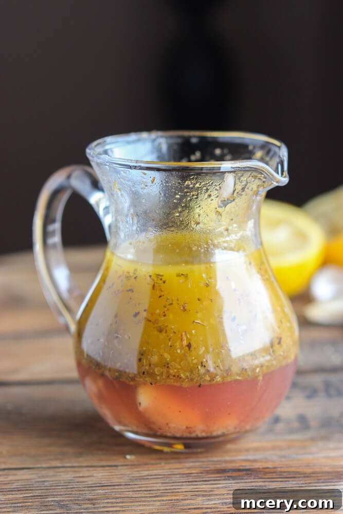 Zoomed out image of Greek dressing in a glass container, ready for use.