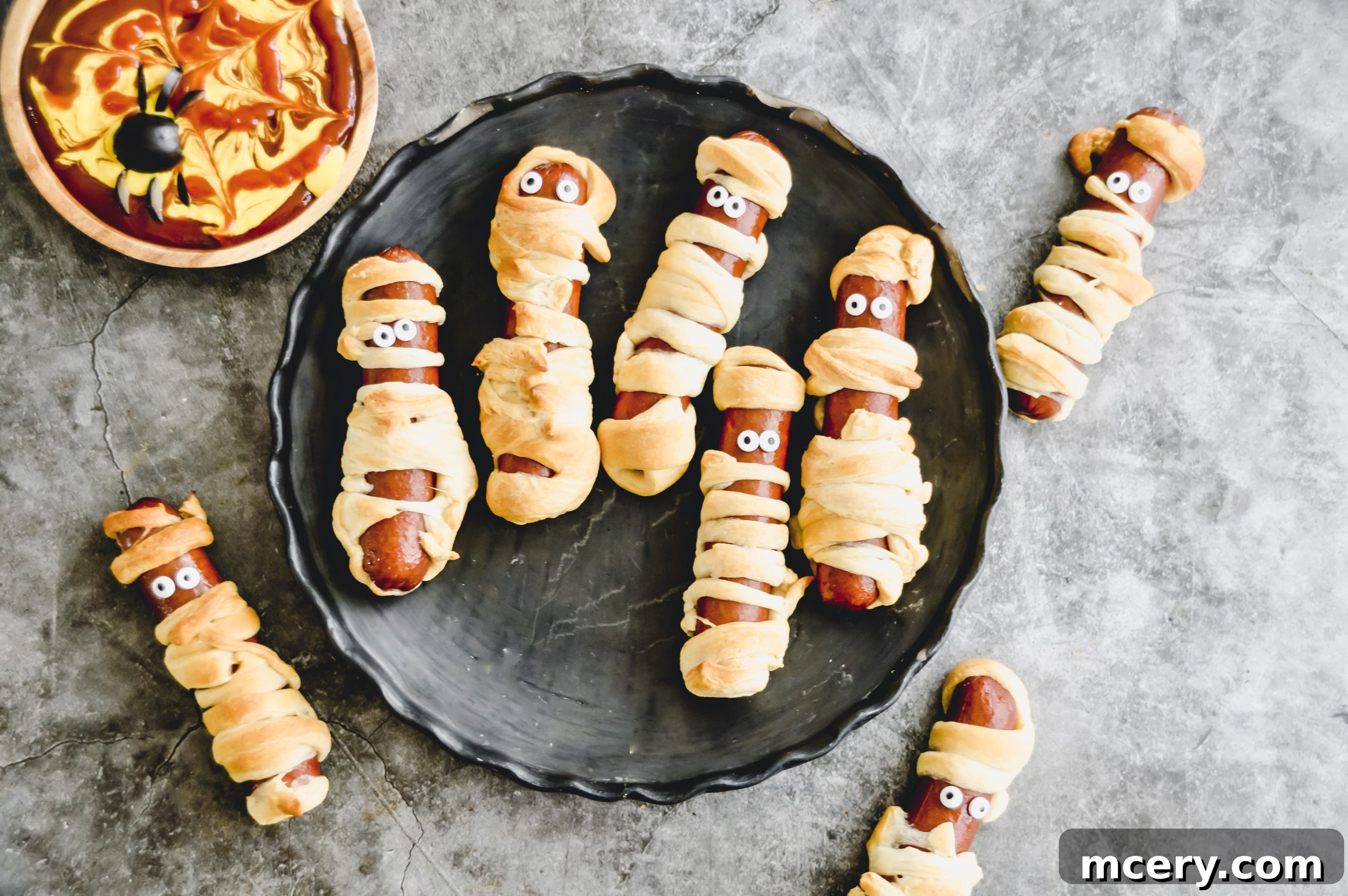 Halloweenie Wraps 3 Close-up of a Mummy Dog, showing the intricate dough wrapping around a hot dog, with a focus on the texture of the baked crescent roll. The ends are slightly frayed, adding to the mummy effect.
