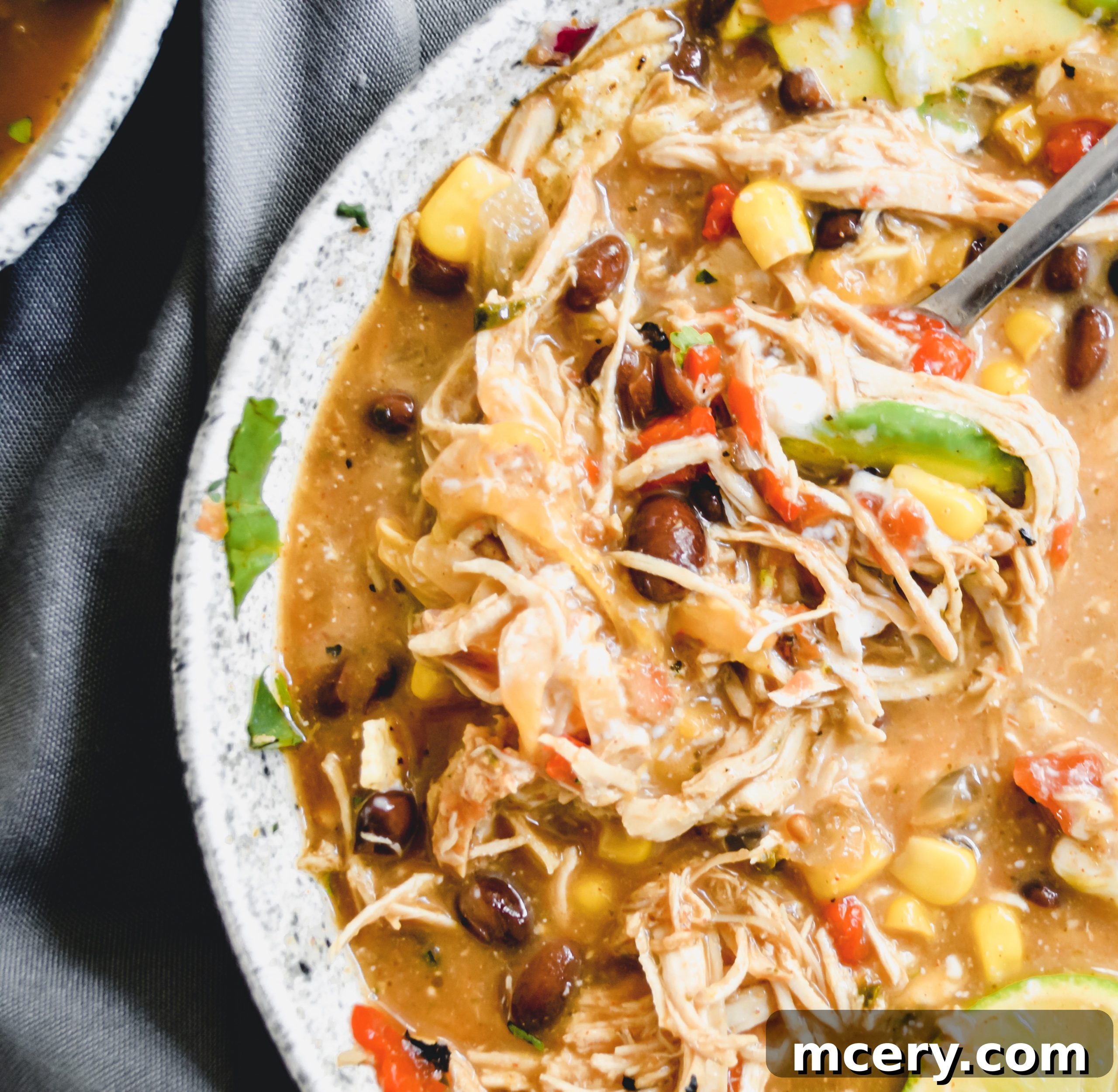 Hearty Slow Cooker Chicken Enchilada Soup 3 Close-up shot of the creamy texture of Chicken Enchilada Soup with visible ingredients like chicken, corn, and beans.