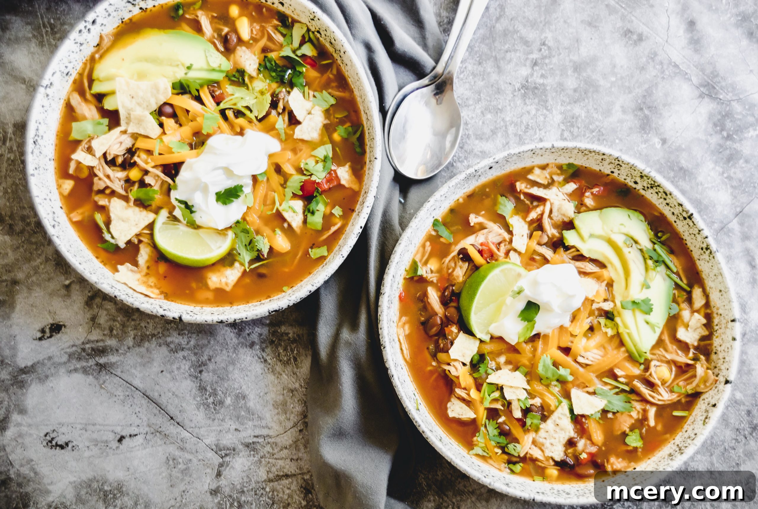 Hearty Slow Cooker Chicken Enchilada Soup 7 A finished bowl of Chicken Enchilada Soup with various toppings like sour cream, cilantro, and tortilla strips.