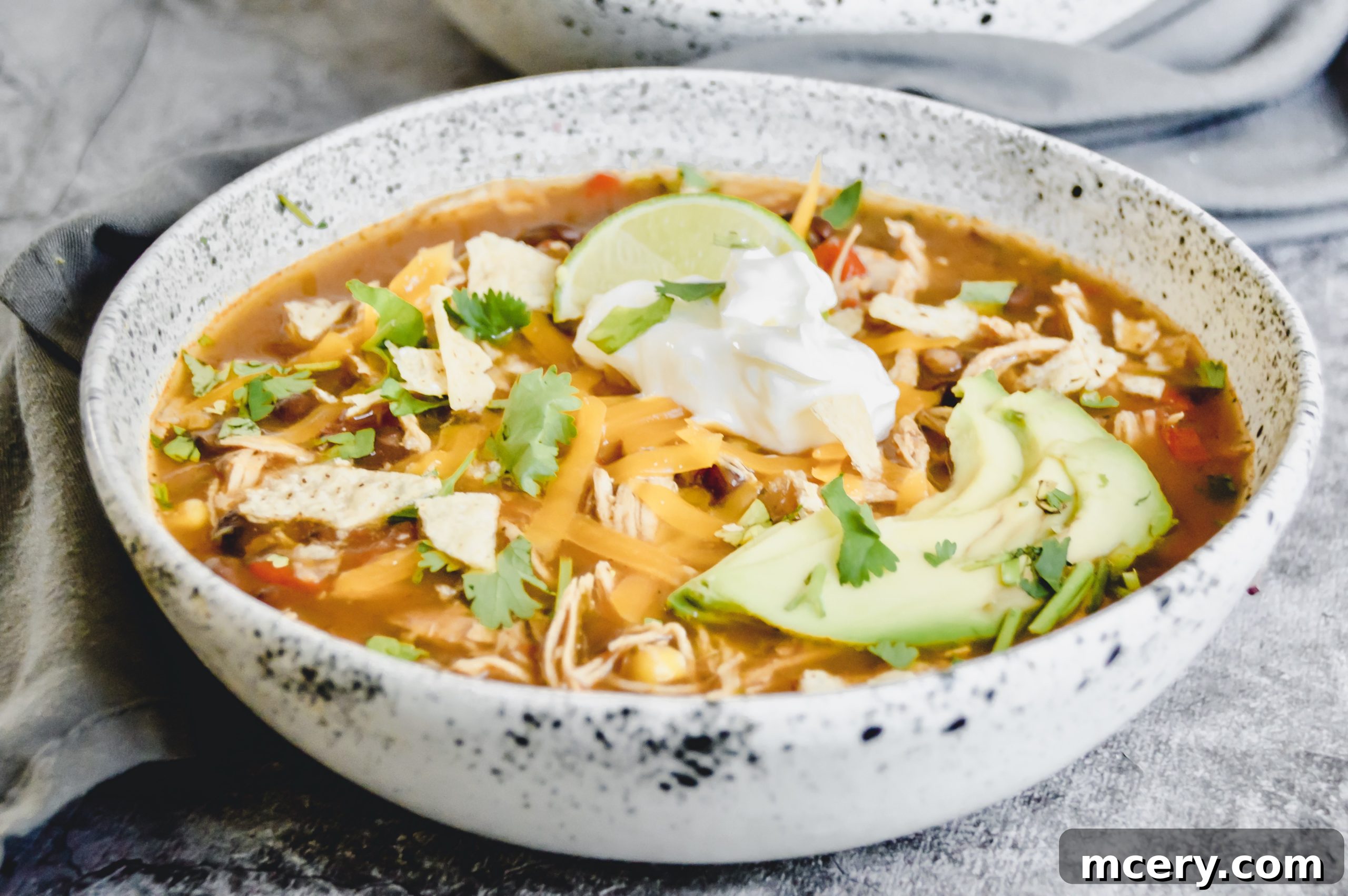 Hearty Slow Cooker Chicken Enchilada Soup 8 A side view of the rich Chicken Enchilada Soup in a bowl, showcasing its depth and vibrant color.
