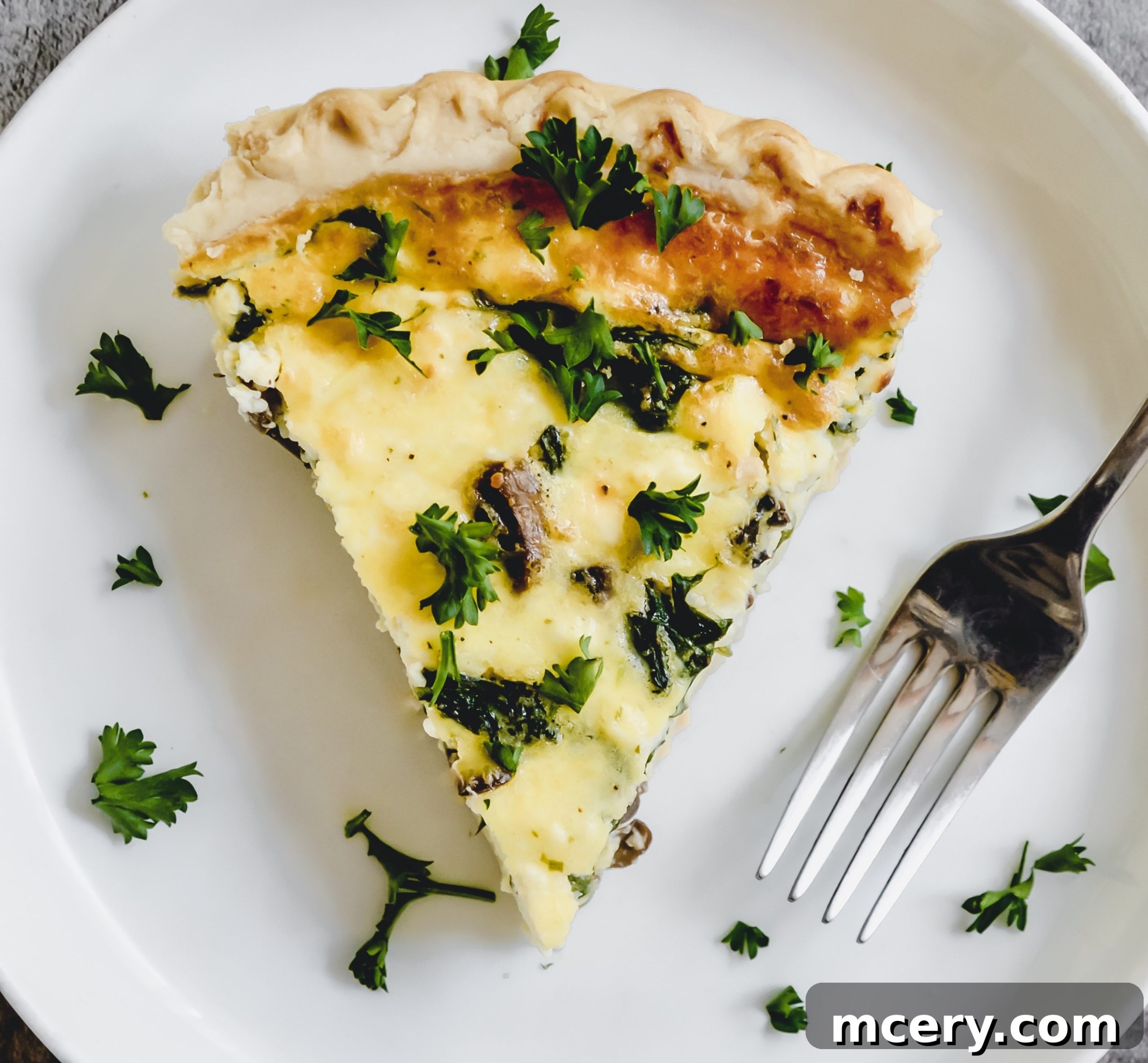 A close-up view of a slice of Spinach, Mushroom, and Feta Quiche, showing the creamy texture and generous vegetable distribution.