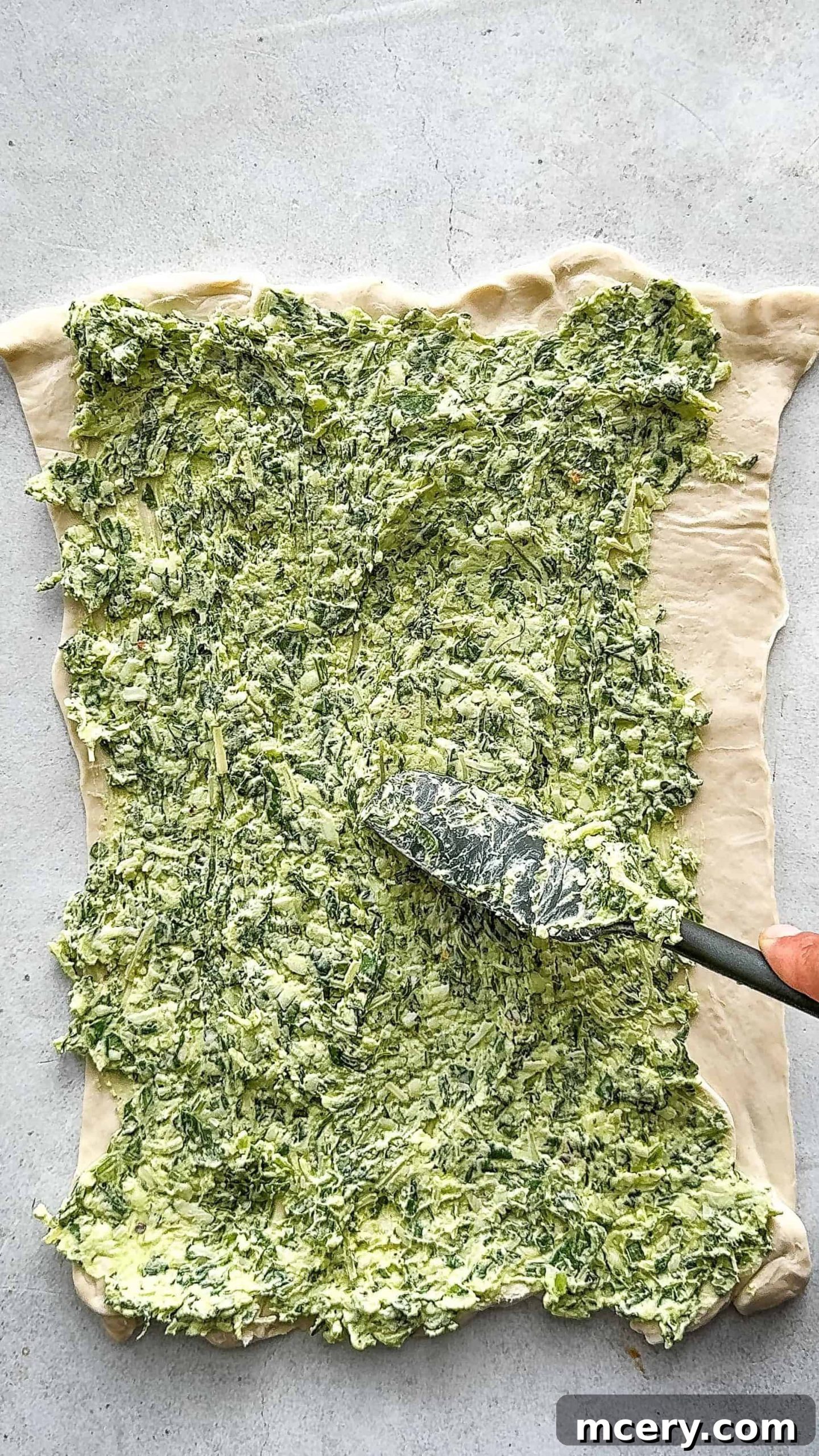 Savory Spinach and Cheese Puff Pastry Swirls 7 Hand picking up a spinach and cheese pinwheel