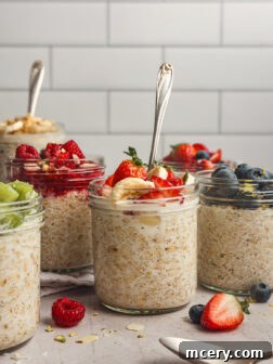 Prepared overnight oats topped with fruit in glass jars.