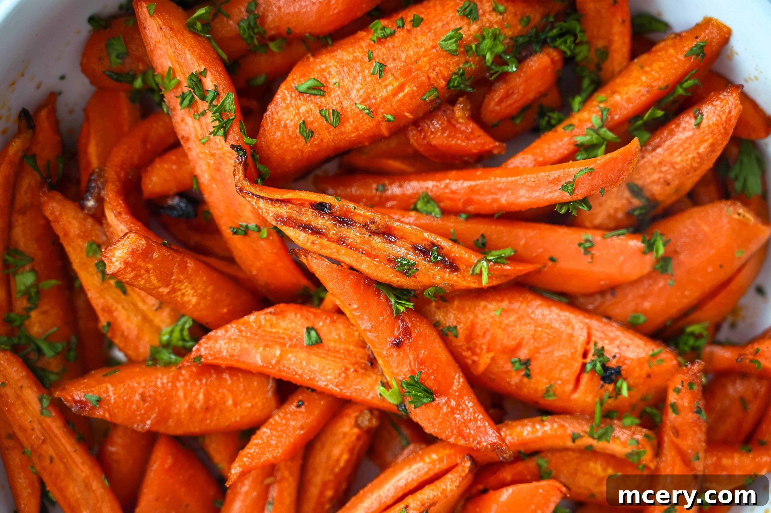 Golden Maple Glazed Carrots 2 Close-up of golden brown maple roasted carrots in a white serving dish, garnished with fresh parsley.
