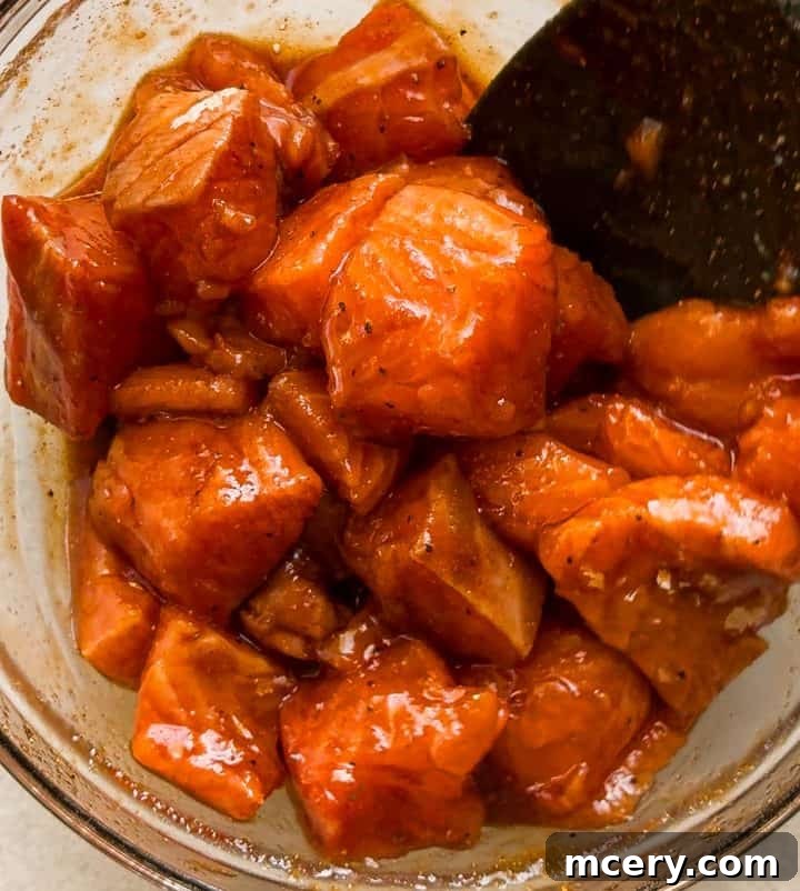 Honey Glazed Salmon Bites with Sesame Ginger and Smoked Paprika 6 Raw salmon cubes tossed in the honey, soy sauce, sesame, and ginger marinade in a glass bowl before air frying.