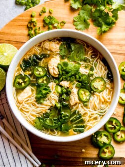 overhead vietnamese chicken noodle soup with fresh herbs and lime wedges