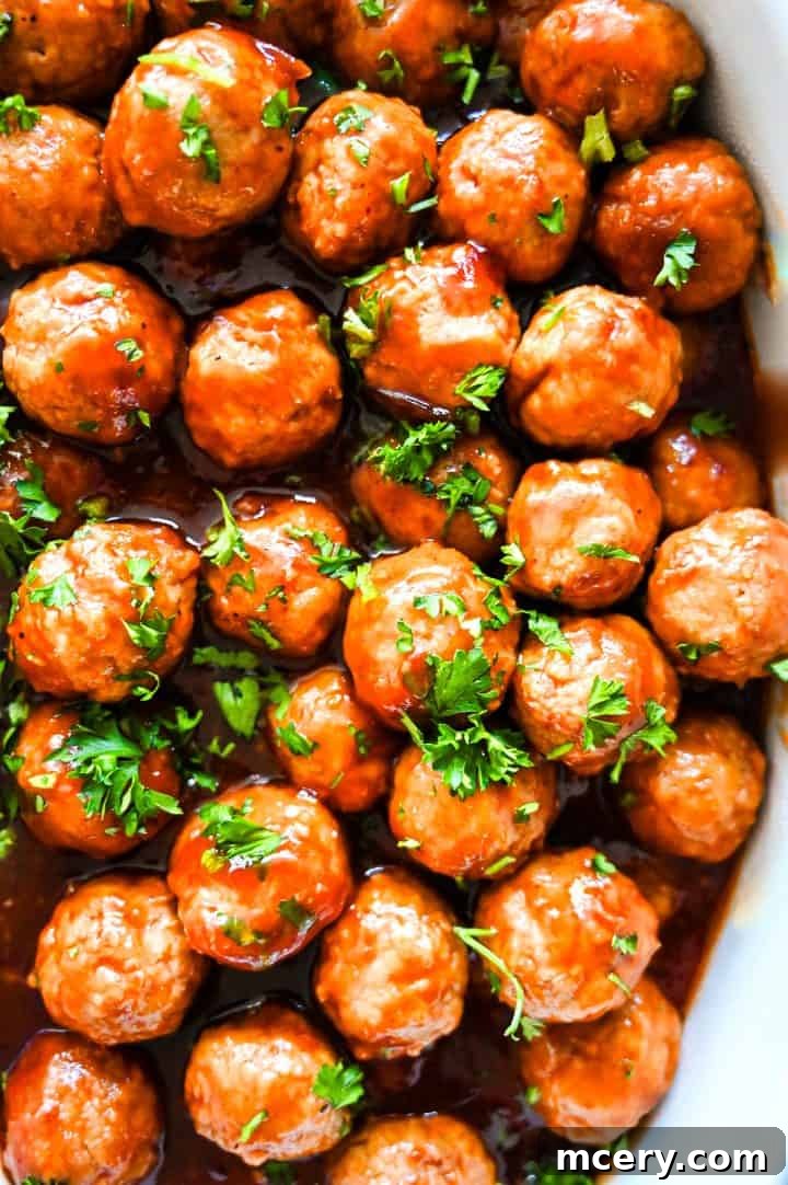 Cranberry Glazed Holiday Meatballs 2 Overhead shot of glazed holiday meatballs topped with fresh parsley, arranged tightly on a baking sheet, ready to be served at a festive gathering.