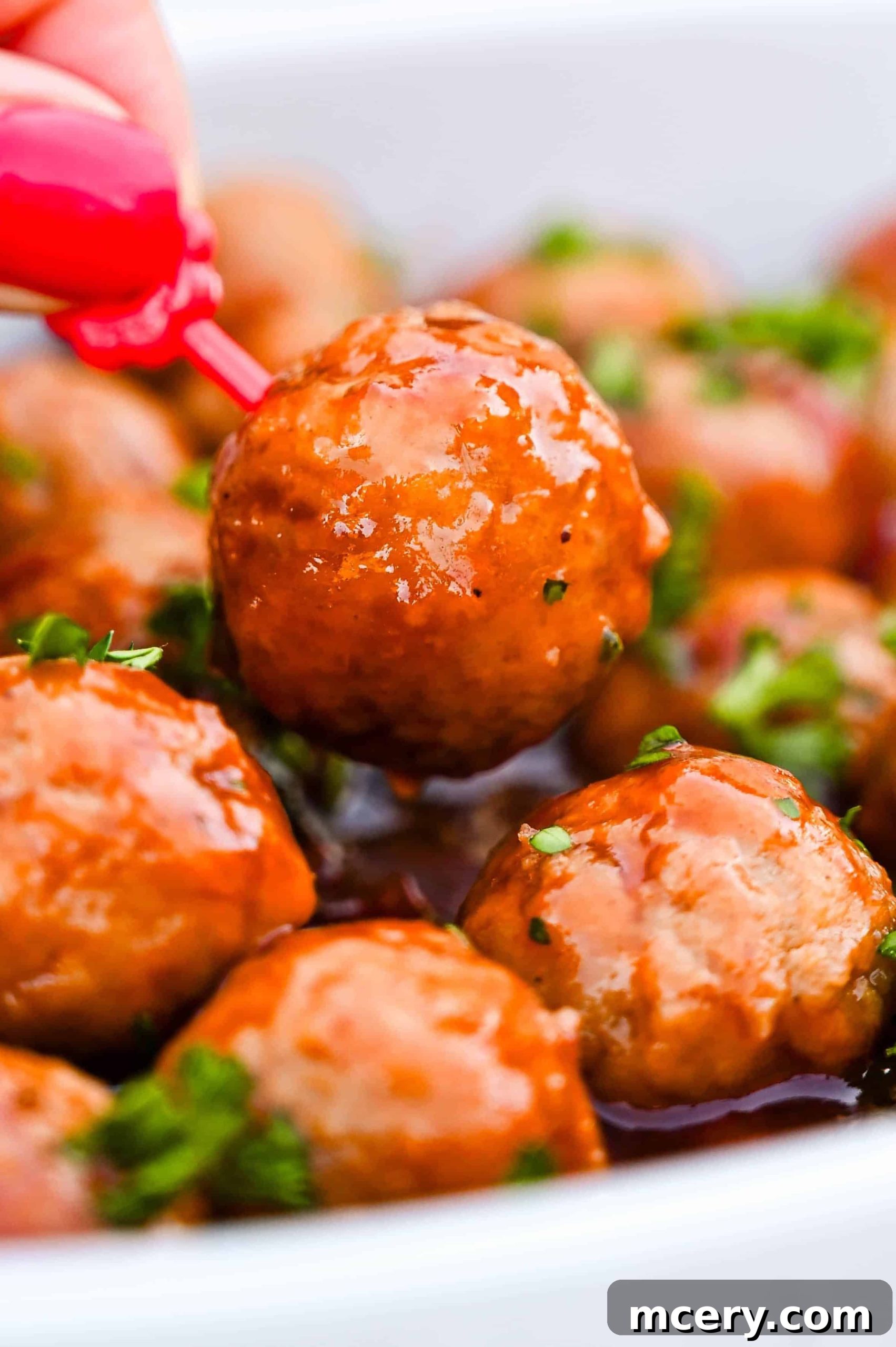 Cranberry Glazed Holiday Meatballs 10 Close-up of a festive bowl of glazed Holiday Cranberry Meatballs, garnished with fresh parsley, ready to be served.