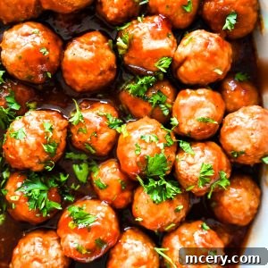 Cranberry Glazed Holiday Meatballs 9 Overhead shot of glazed holiday meatballs topped with fresh parsley, arranged tightly on a baking sheet, with a festive holiday background.
