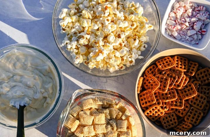 Ingredients for Reindeer Crunch Snack Mix displayed in bowls, including popcorn, Chex cereal, pretzels, crushed peppermint, and melted white chocolate.