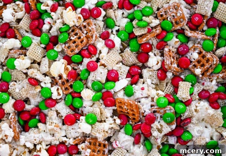 Broken pieces of Reindeer Crunch Snack Mix spread on parchment paper, showcasing the white chocolate coating and colorful inclusions.
