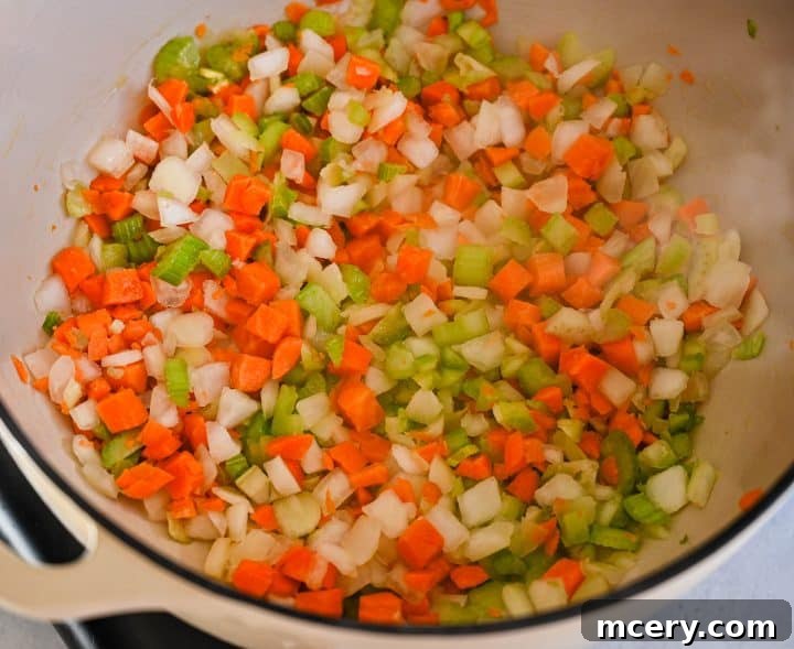 Soul Soothing Chicken Noodle Soup 5 Onion, carrots, and celery sautéing in a large pot with olive oil and butter, releasing their sweet aromas.