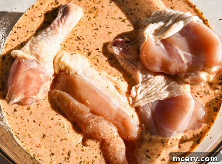 Raw chicken pieces arranged on a baking sheet before cooking.