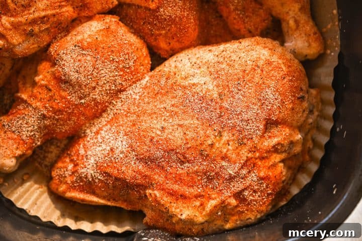 Fresh raw chicken breasts coated with seasoned herbs ready for cooking.