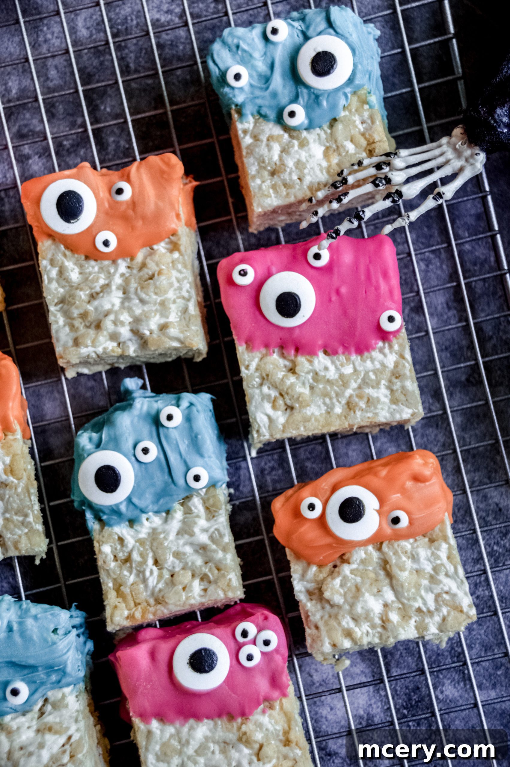 Spooktacular Rice Krispie Treats 2 Colorful Monster Rice Krispies Treats with candy eyes, arranged on a tray, ready for a Halloween party.
