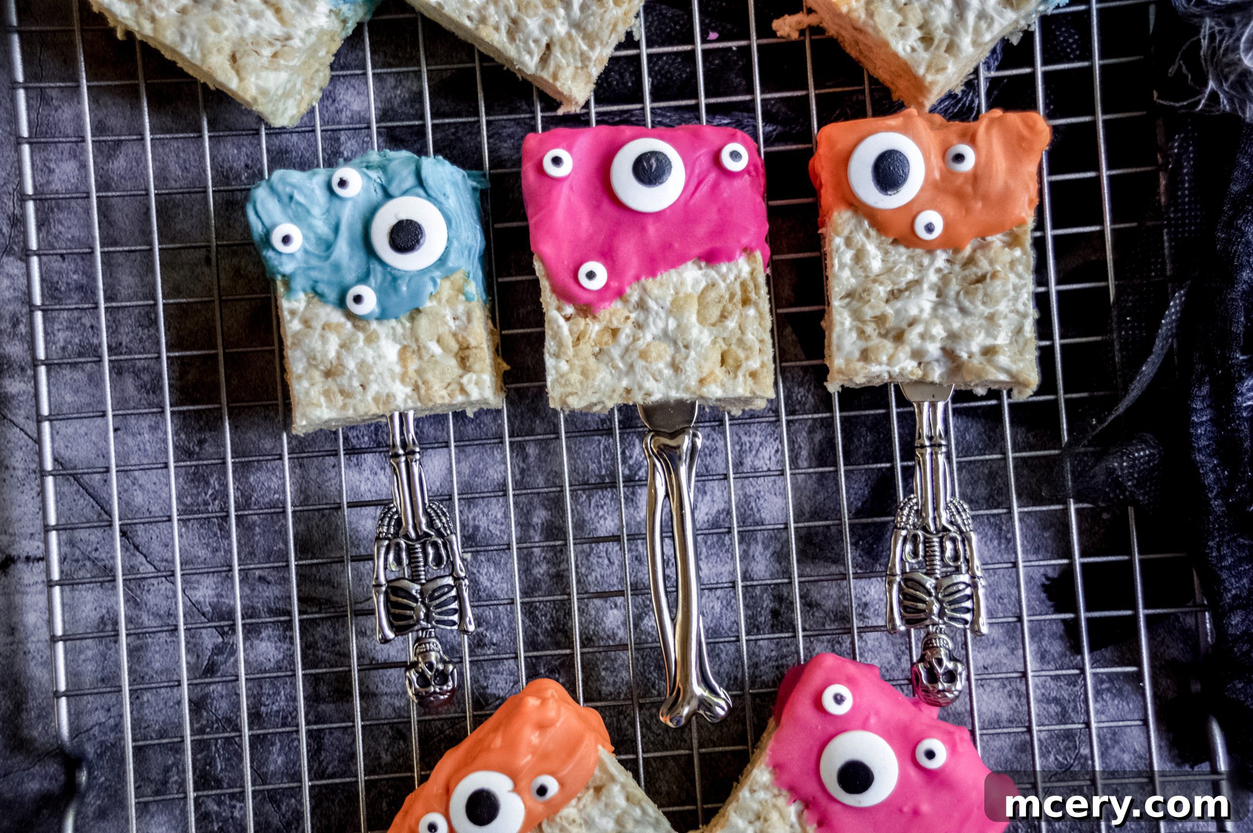 Spooktacular Rice Krispie Treats 4 An overhead shot of several Monster Rice Krispies Treats arranged on parchment paper, highlighting their various colors and expressions.