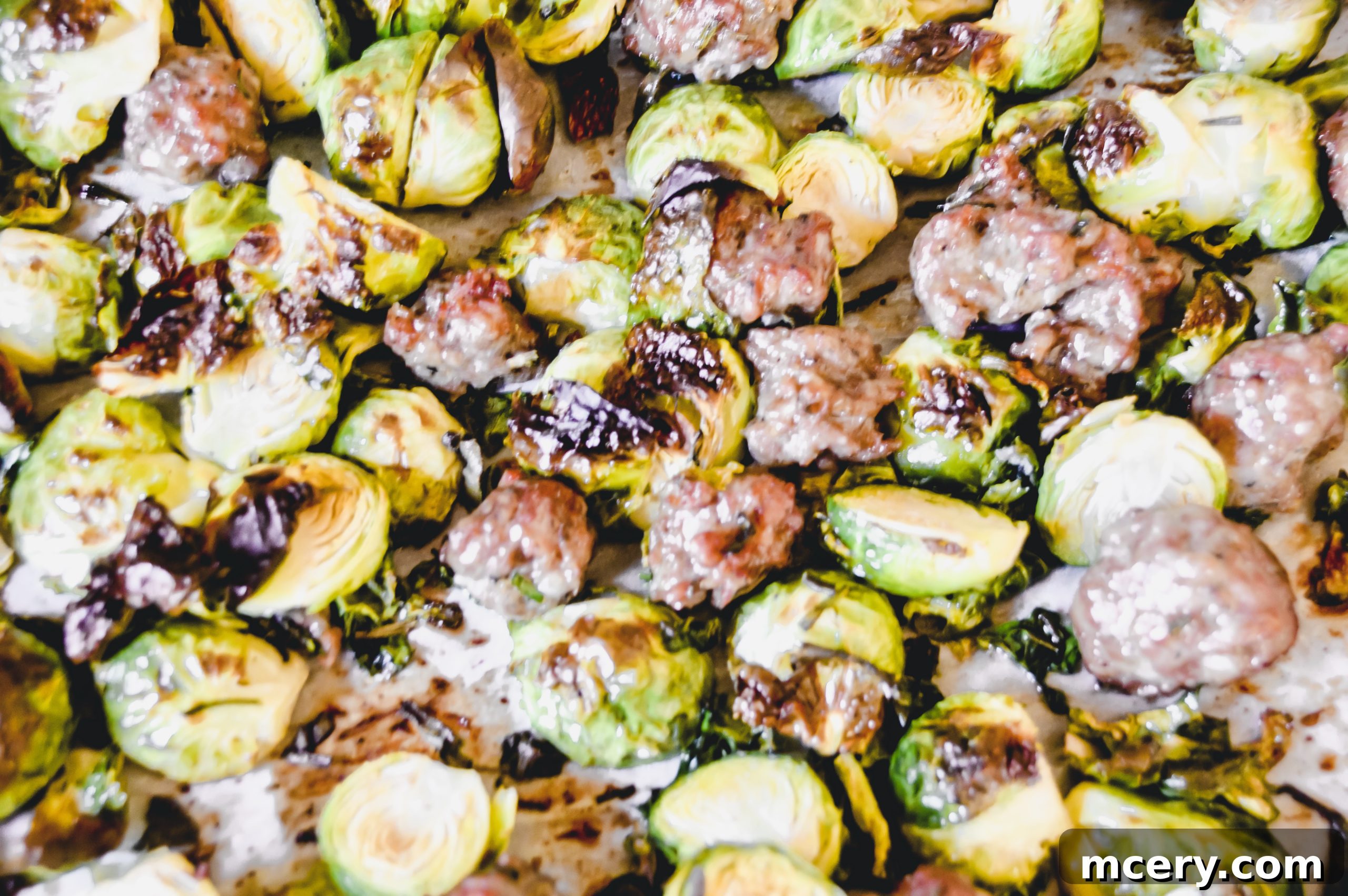 A wider shot of roasted Brussels sprouts and Italian sausage, showcasing the vibrant colors and appealing texture of the dish.