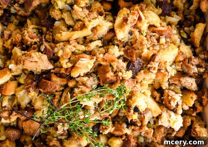 Pratik İç Harcı Tarifi: Şükran Günü Sofralarının Yıldızı 11 A close-up image of Easy Stuffing. The mixture includes various pieces of bread, some toasted, and appears to be seasoned with herbs and spices. A sprig of fresh thyme rests on top, adding a touch of green to the golden-brown dish.