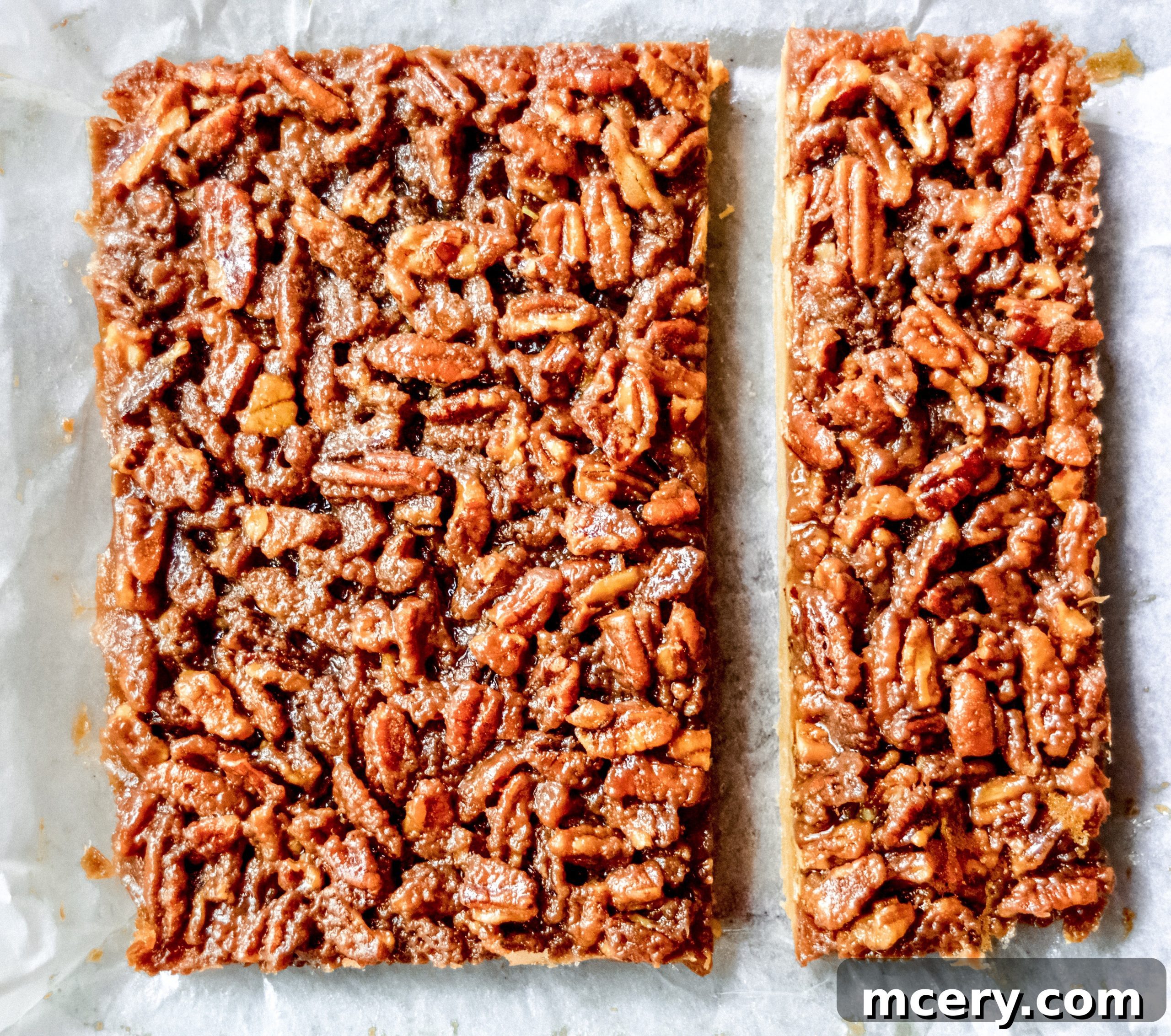 Several Pecan Pie Bars served on a white plate, showcasing their inviting golden-brown crust and glistening pecan topping.