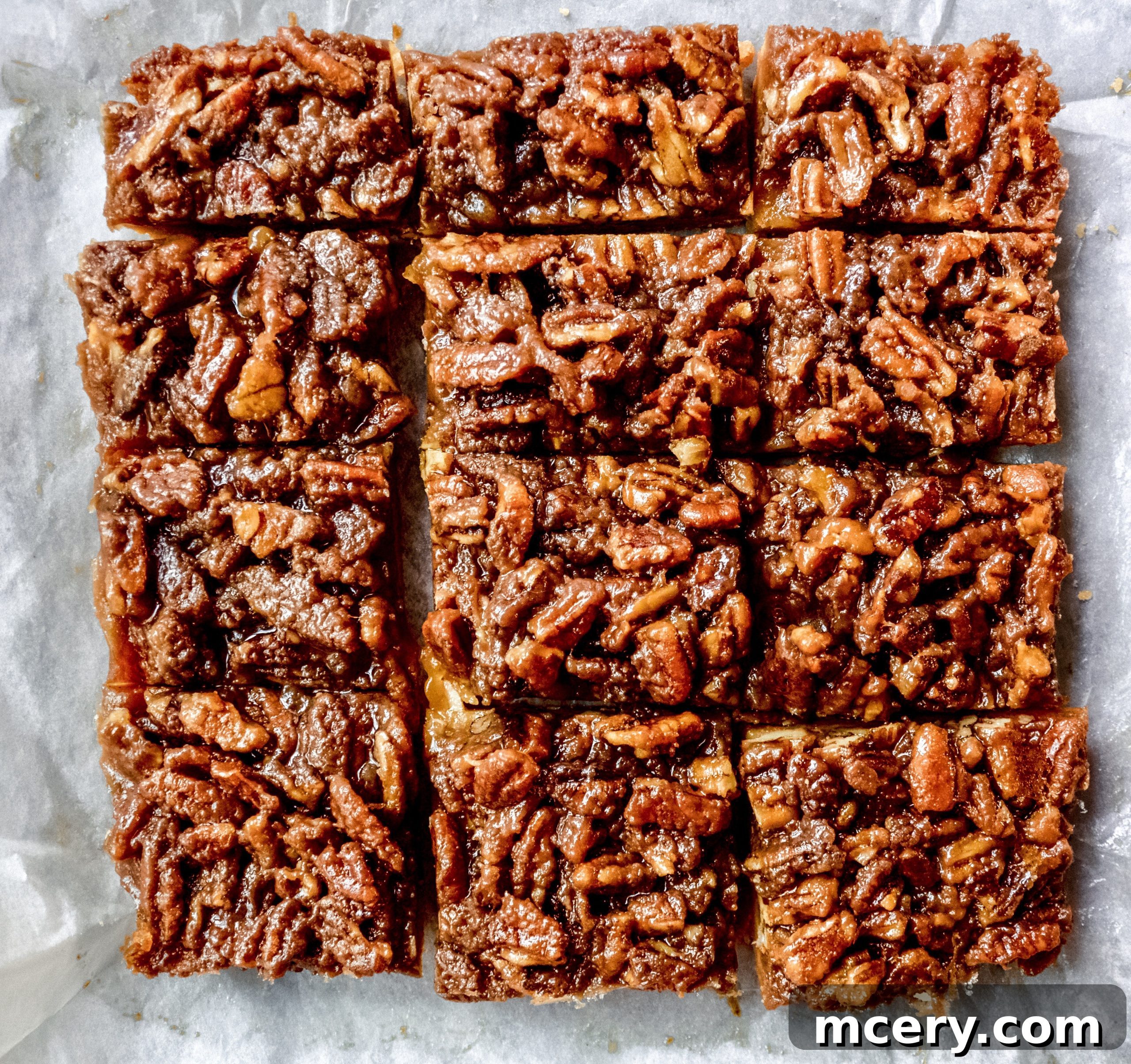 A stack of perfectly cut Pecan Pie Bars on a white plate, ready to be served.