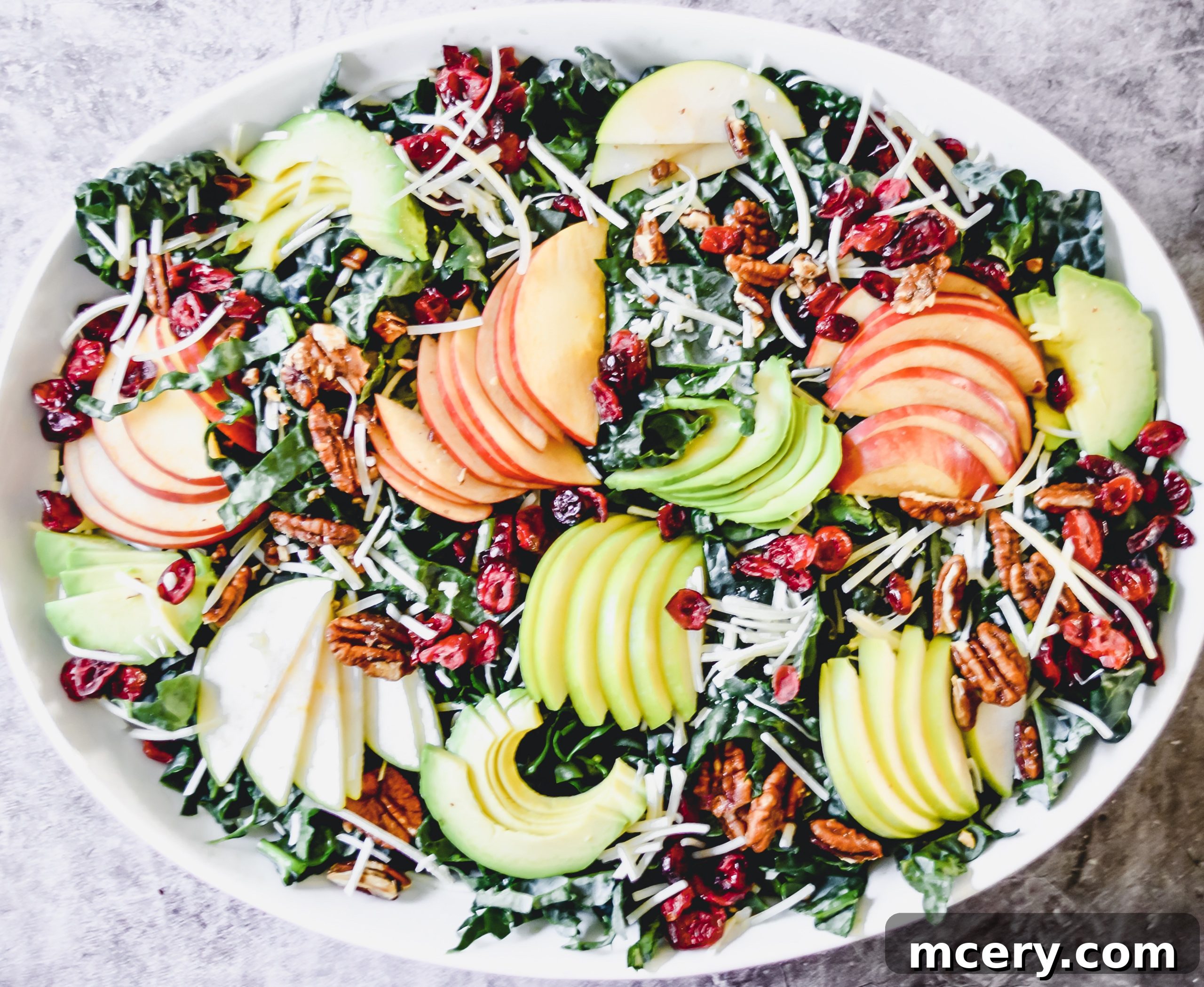 Close-up shot of the Tuscan Kale Salad, highlighting the texture of the kale leaves, creamy avocado, and bright cranberries.