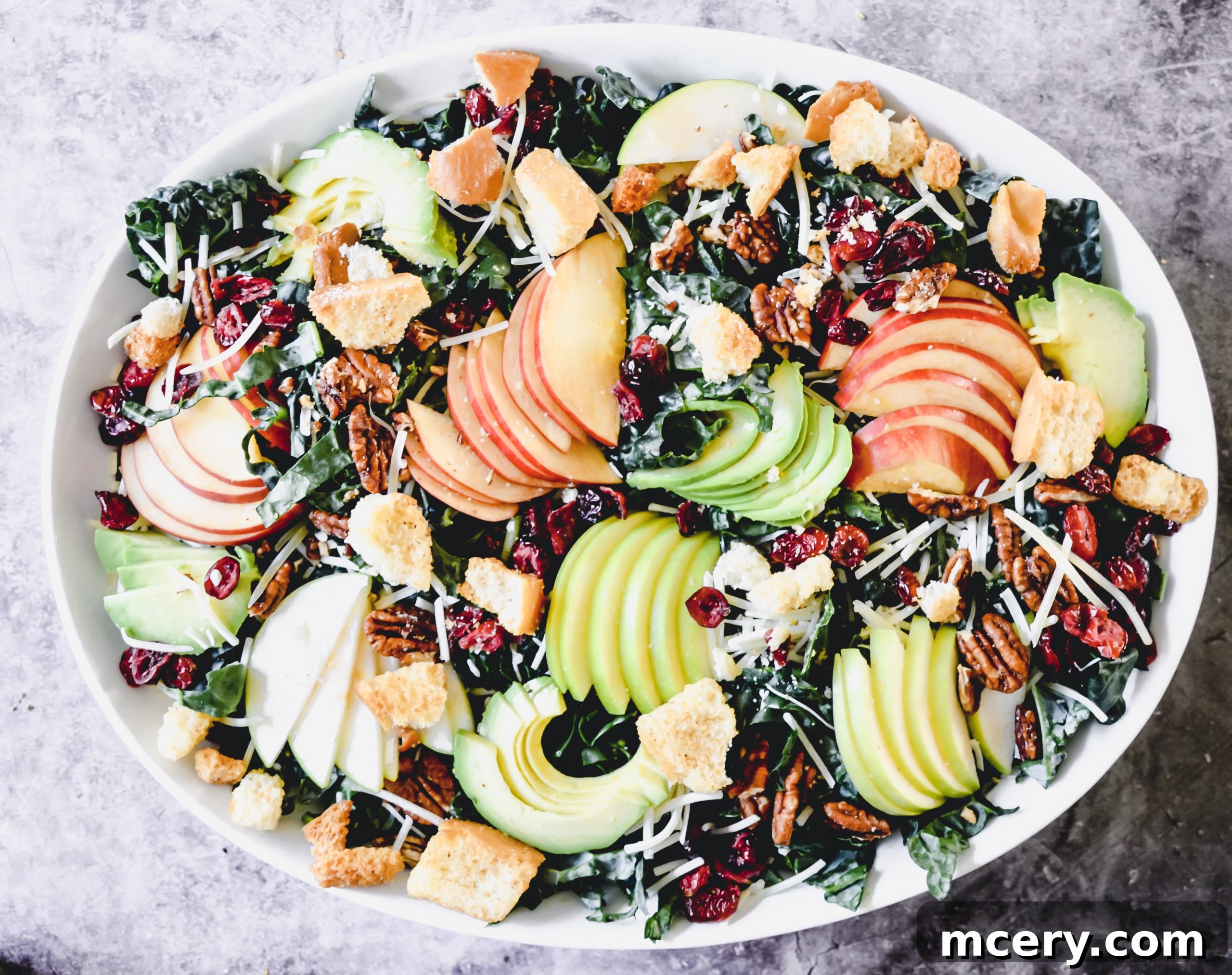 A close-up of the salad showing the thinly sliced apples, pecans, and the rich green kale.