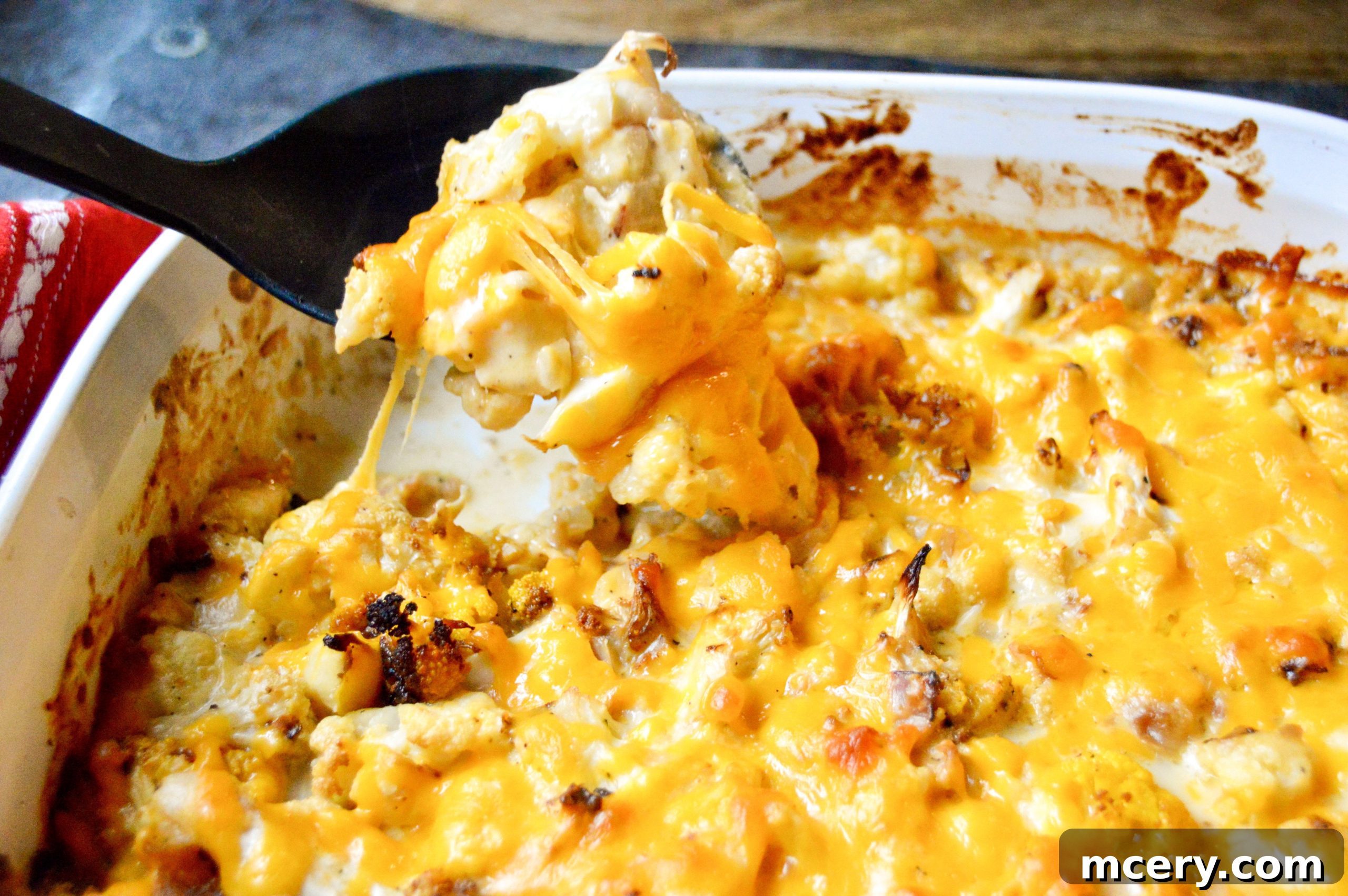Golden Baked Cauliflower Mac & Cheese 8 A close-up of a serving of cauliflower mac and cheese, showing the creamy texture and tender cauliflower florets, garnished with fresh herbs.