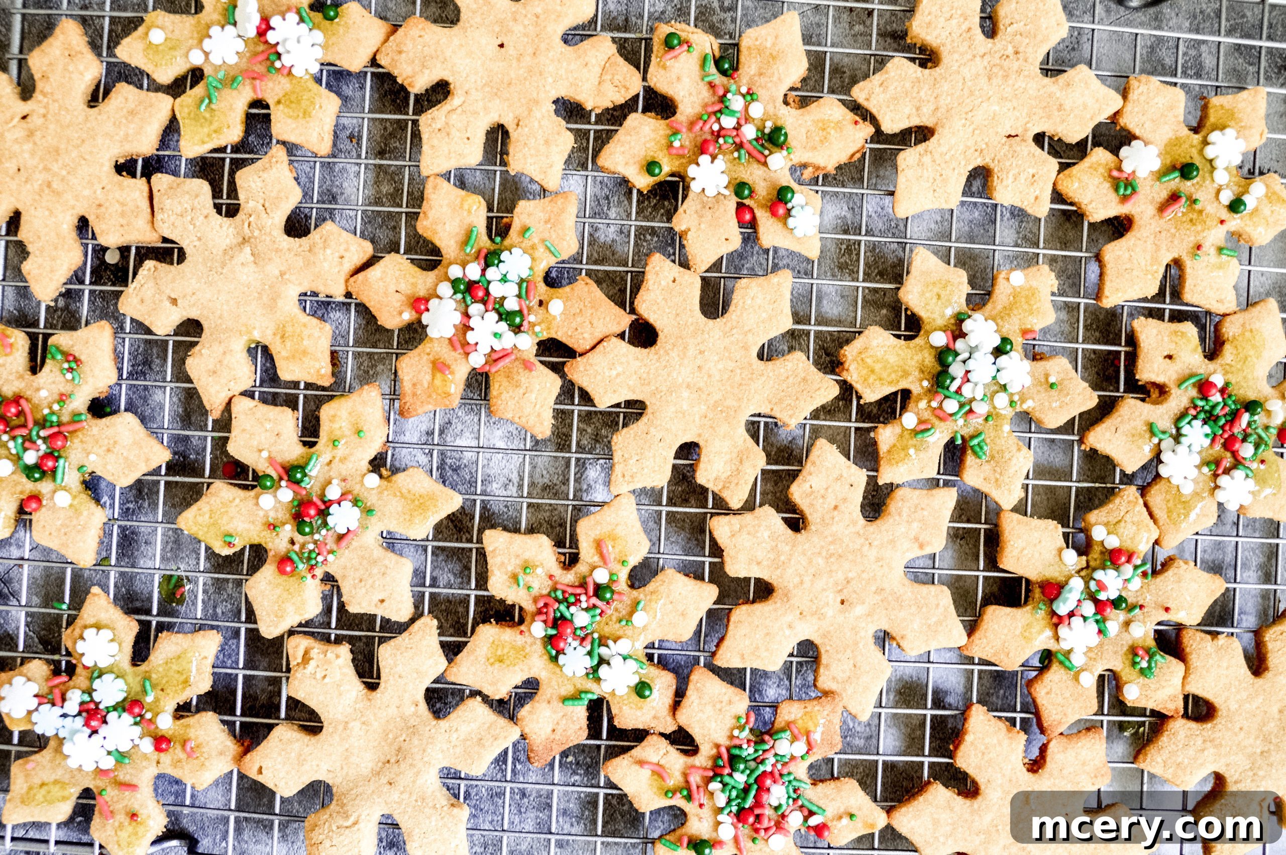 Guilt-Free Paleo Vegan Cut-Out Sugar Cookies 9 Several festive paleo sugar cookies, some decorated with icing and sprinkles, arranged artfully with a few pine sprigs and berries for a holiday theme.