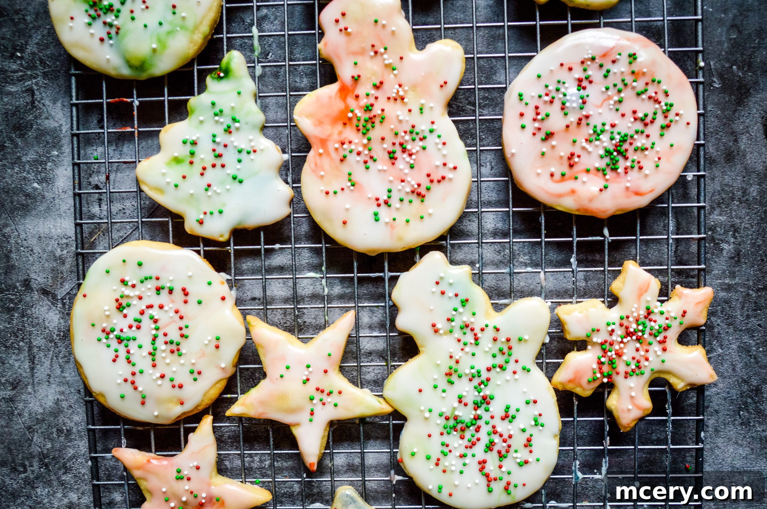 A variety of unbaked sugar cookie dough cutouts, including stars and rounds, arranged on a baking sheet, ready for the oven.