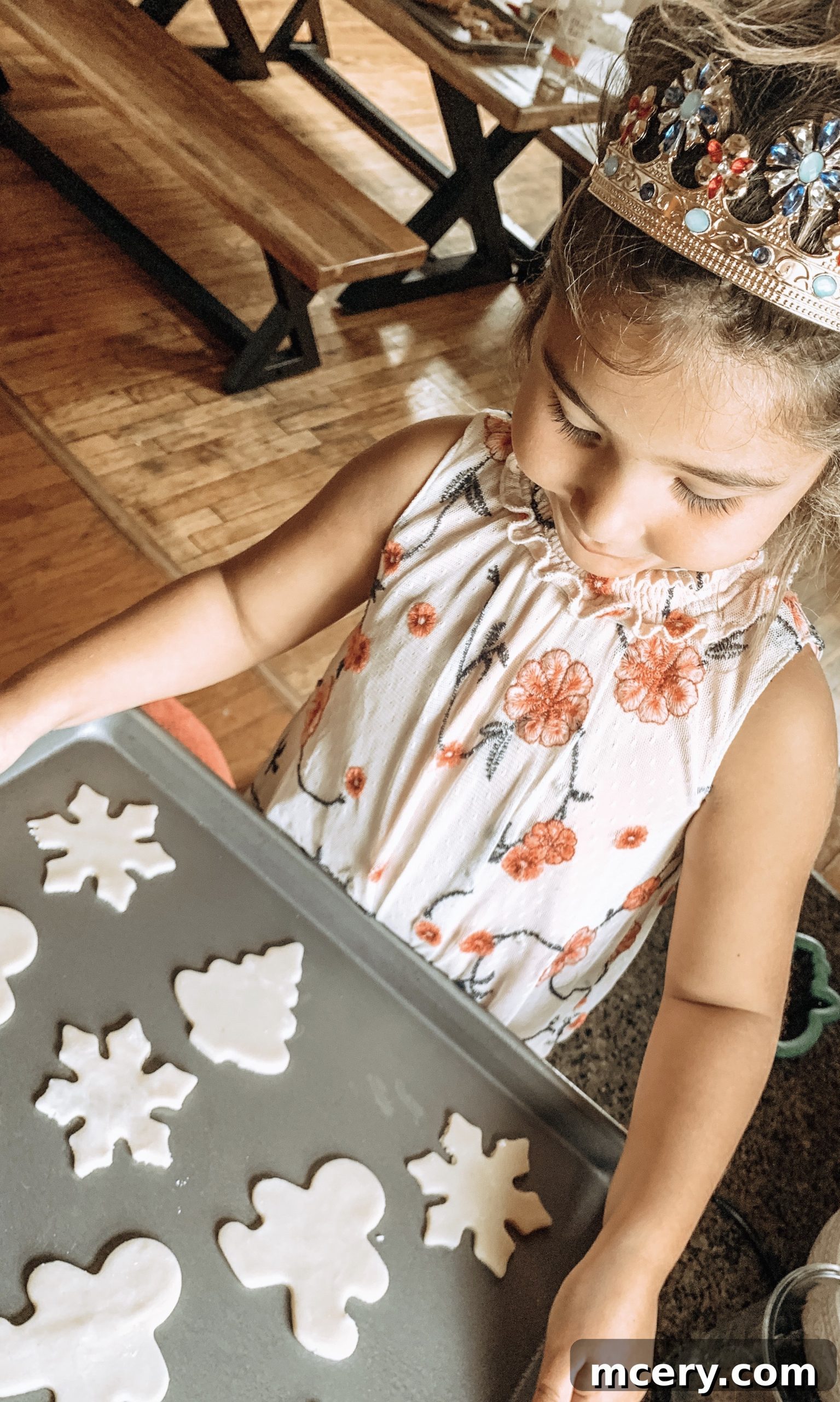 Hands using a star-shaped cookie cutter on rolled-out sugar cookie dough, with other cutouts nearby.