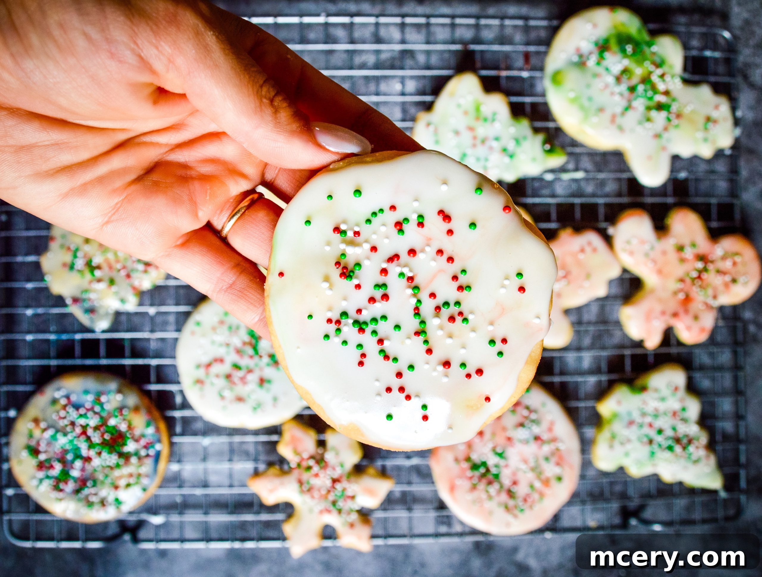A close-up shot of several sugar cookies in various stages of baking, with some beginning to turn golden at the edges.