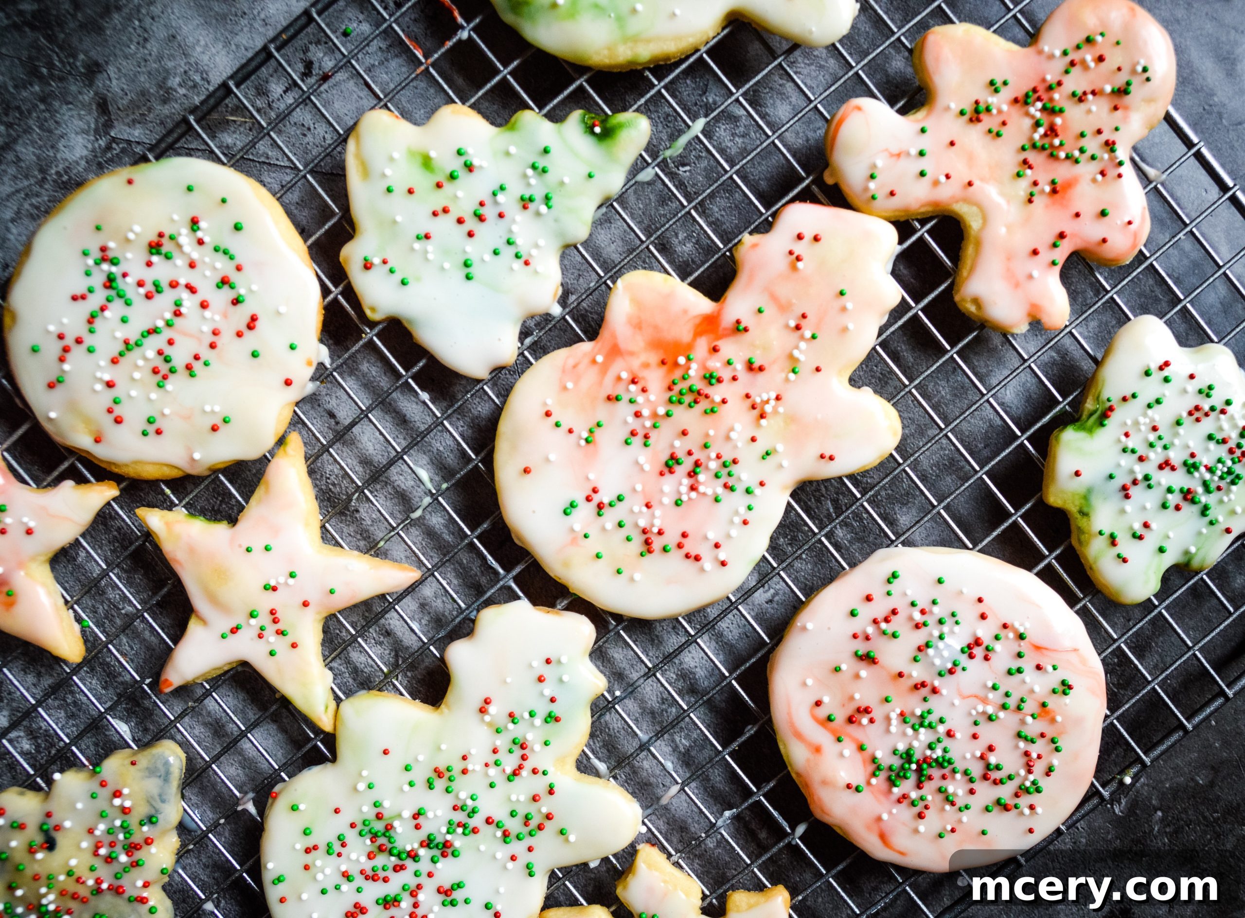 Freshly baked sugar cookies, some still warm, cooling on a wire rack with a golden-brown hue.