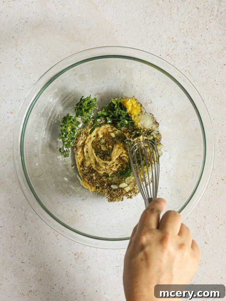Marinade ingredients being whisked together in a clear glass bowl, showcasing a smooth, golden mixture.