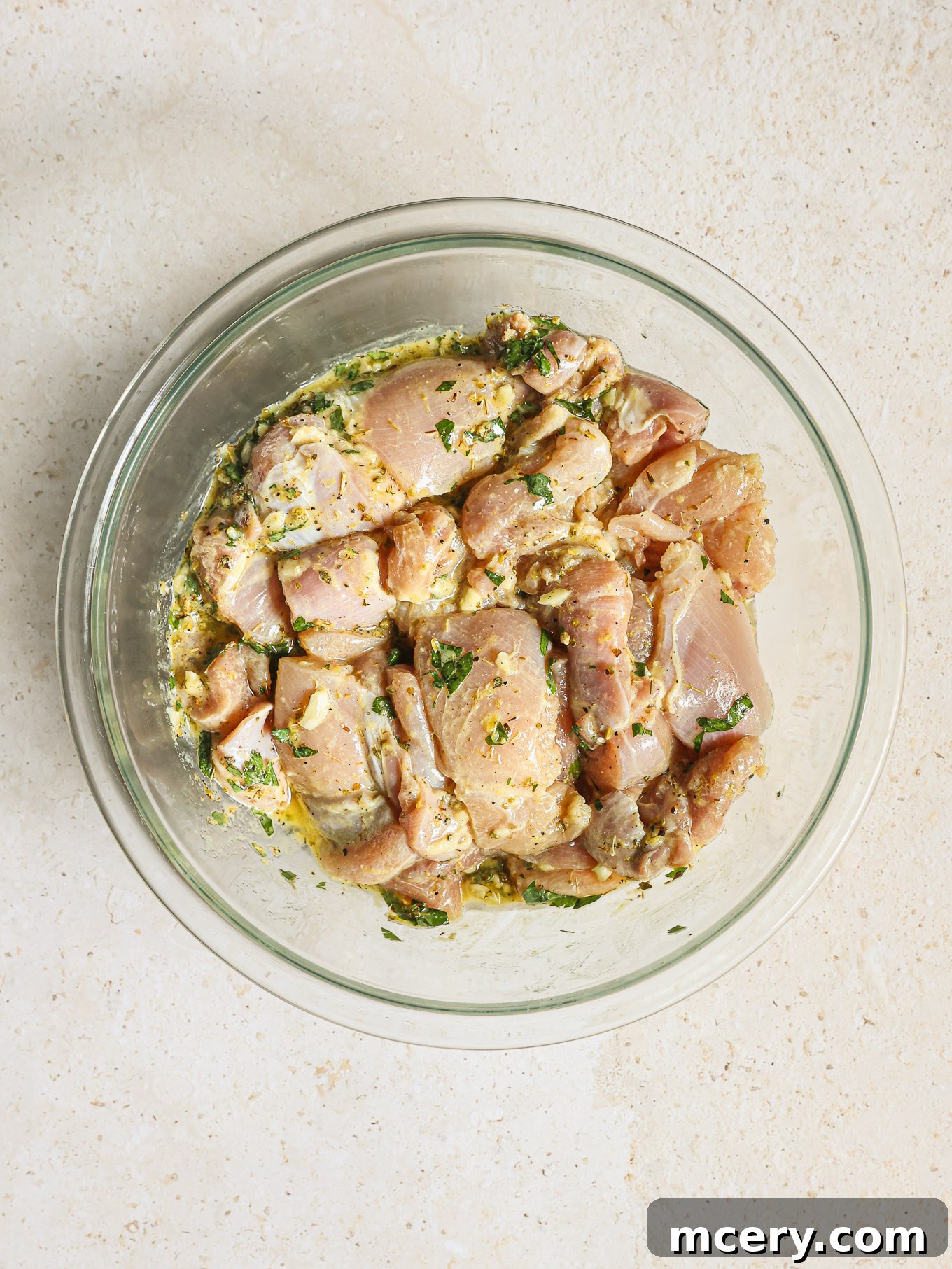 Chicken pieces thoroughly coated in marinade in a glass bowl, ready for refrigeration.
