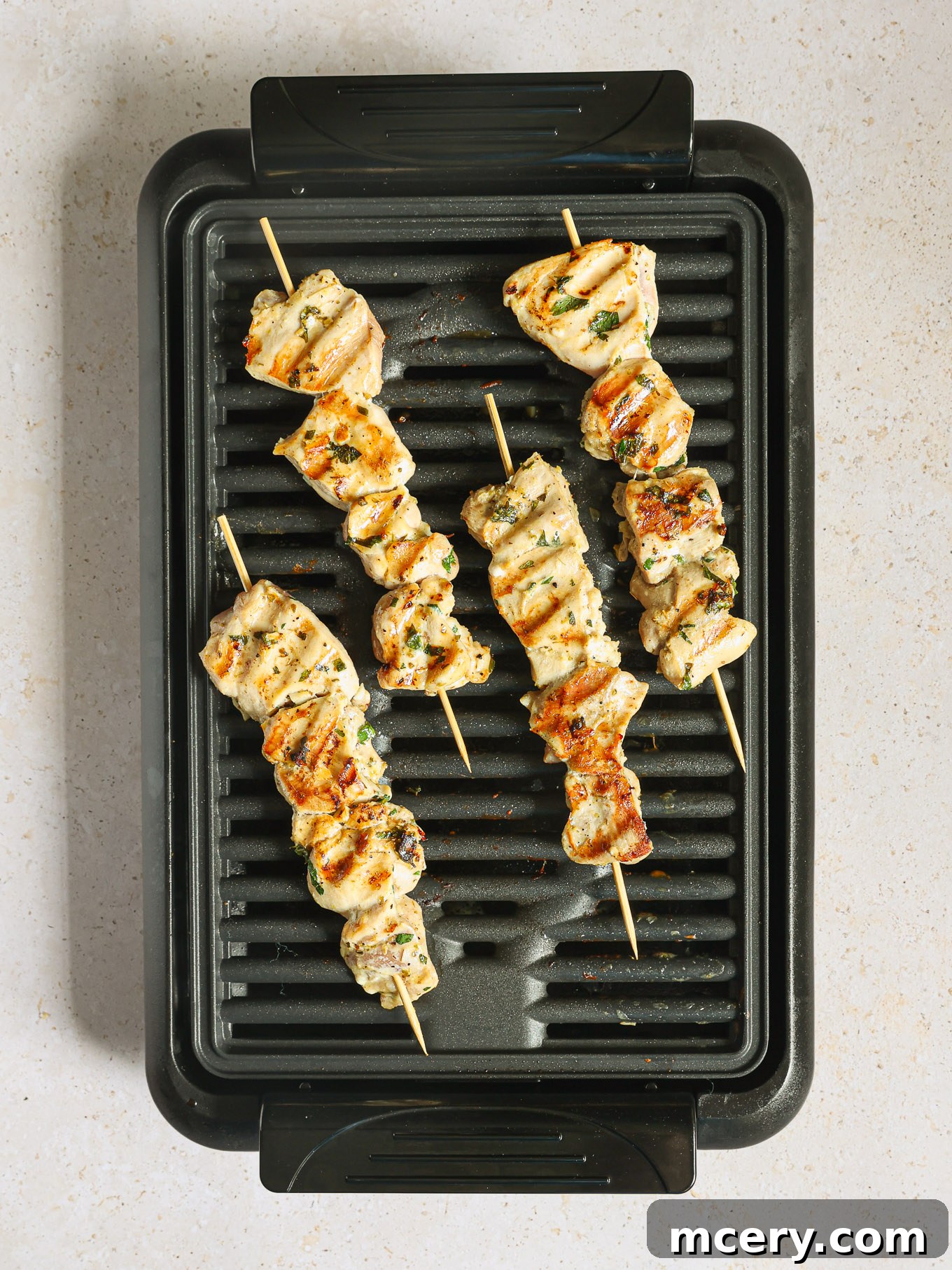 Chicken kabobs sizzling on a hot grill, showing developing char marks.