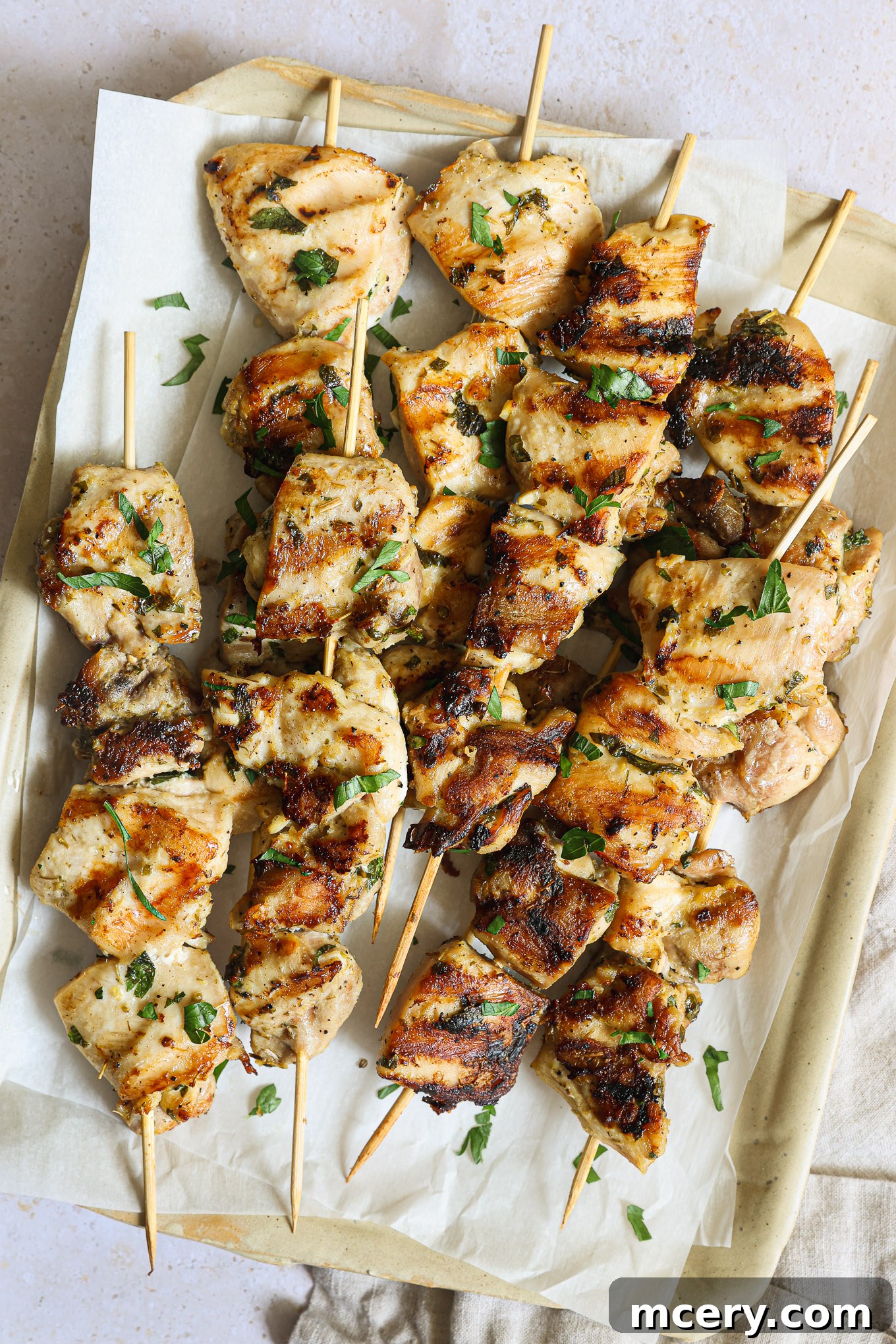 Close-up of perfectly grilled chicken skewers resting on a white platter, ready to be served.