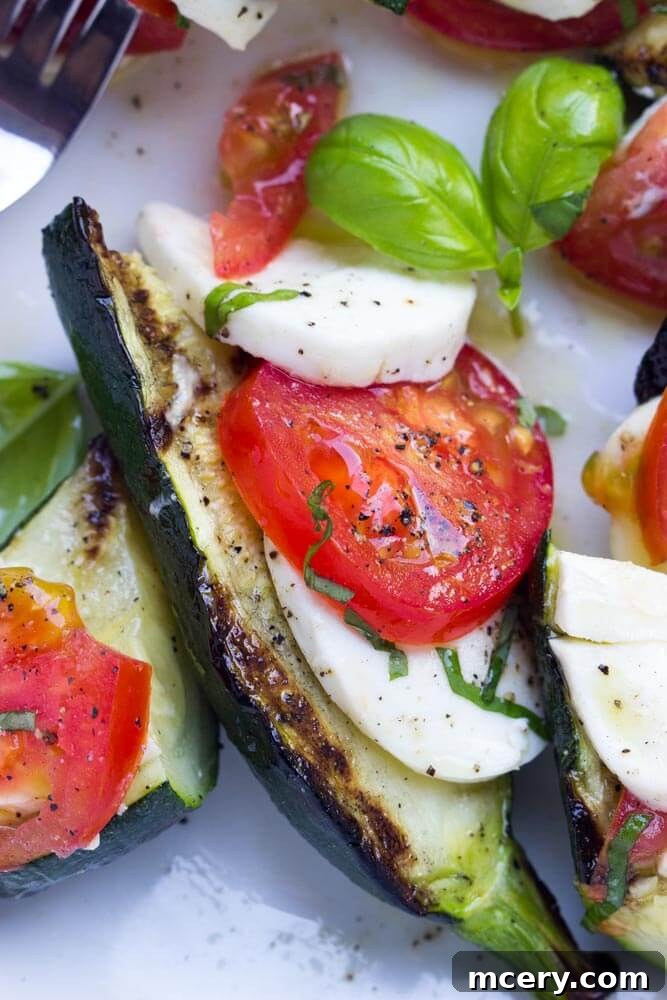 Zucchini Mozzarella Melt 4 Close up of grilled zucchini topped with caprese salad components: mozzarella, tomatoes, and basil