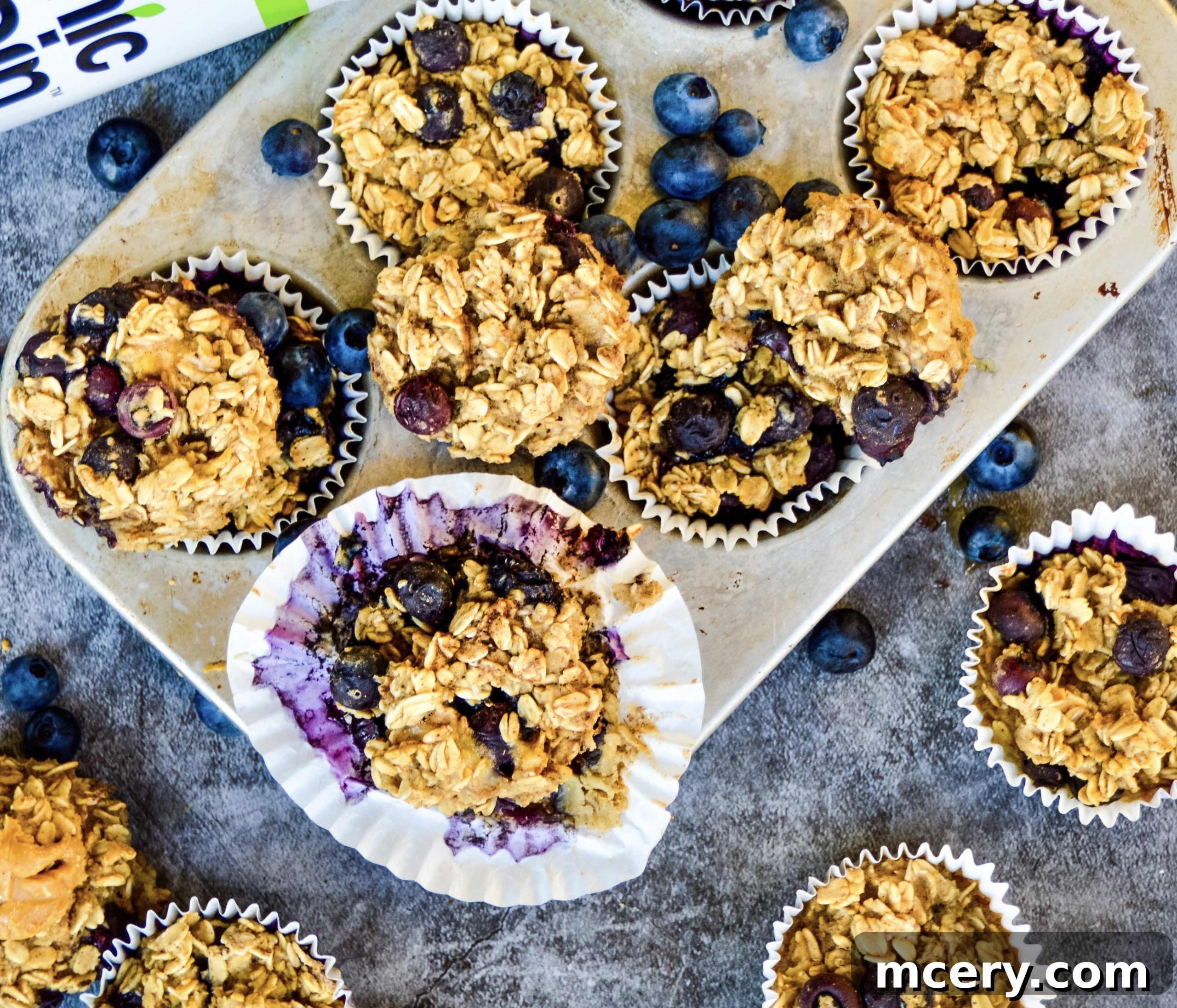 Grab-and-Go Blueberry Protein Oatmeal Cups 5 An overhead shot of two Blueberry Protein Oatmeal Cups on a plate, garnished with fresh blueberries and a spoon, ready to be eaten.