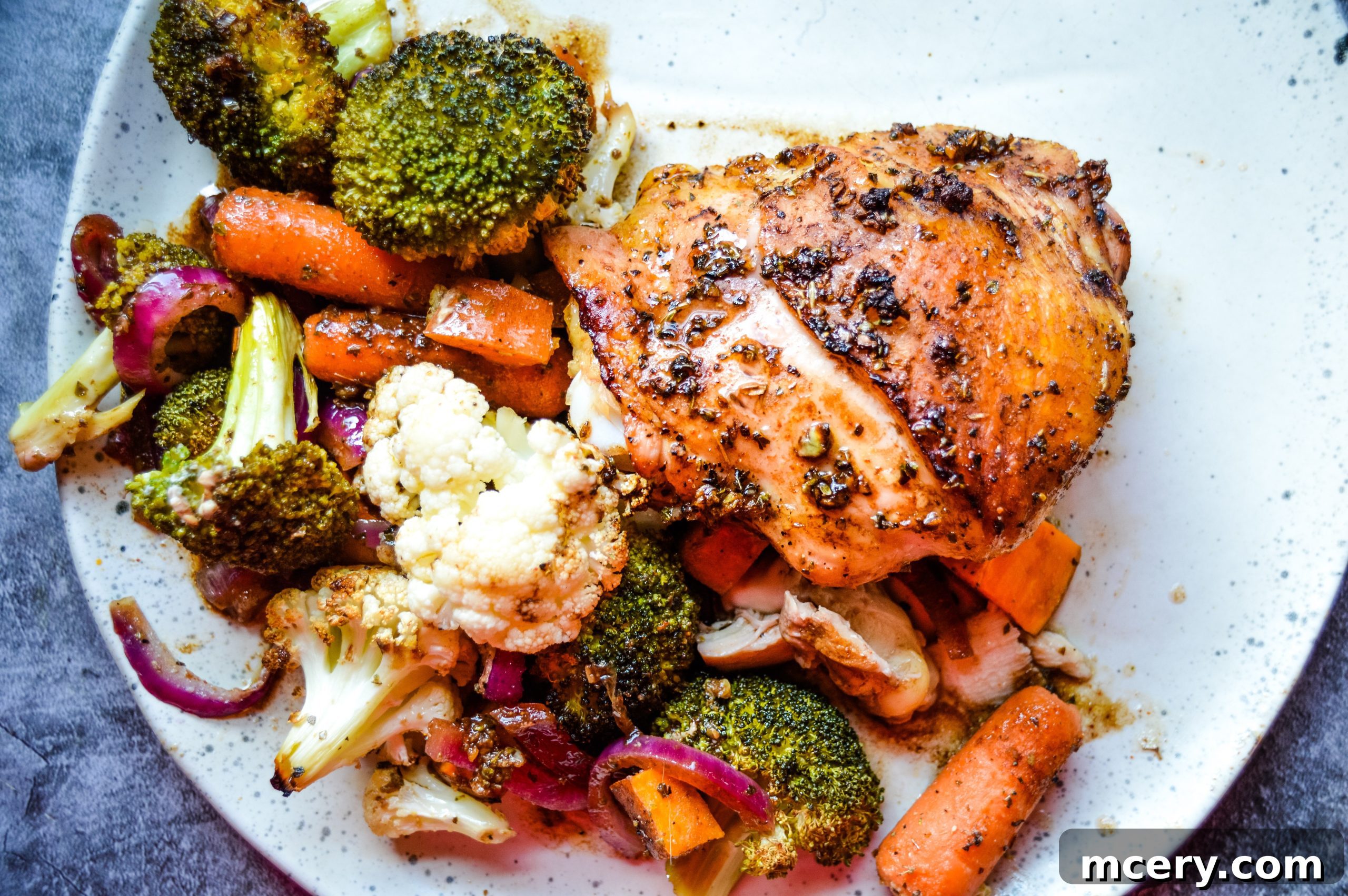 A delicious serving of Balsamic Honey Sheet Pan Chicken and Veggies on a white plate, showcasing the rich colors and textures.